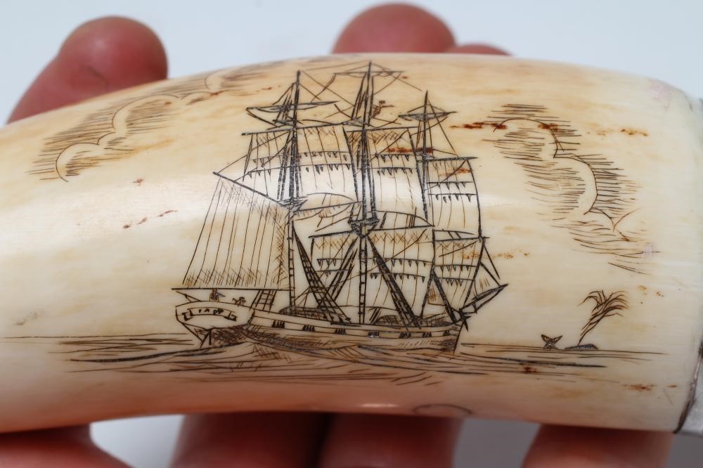 A SCRIMSHAW engraved  with a three masted sailing ship off a palm island below clouds on a stained Image