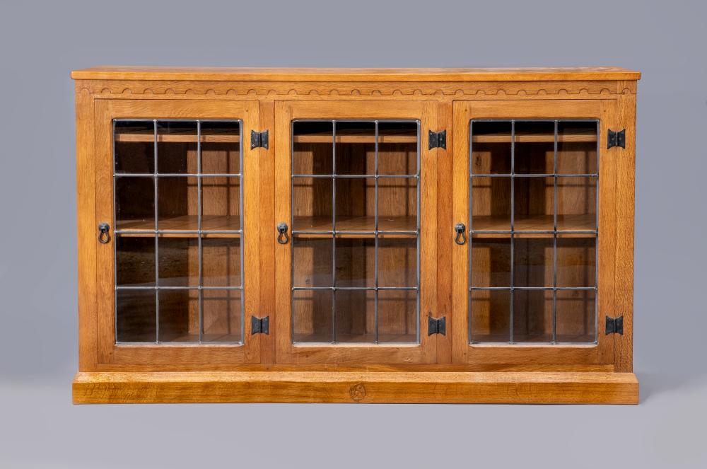 A WILF HUTCHINSON ADZED OAK BOOKCASE of low oblong form with three leaded glazed doors enclosing Image