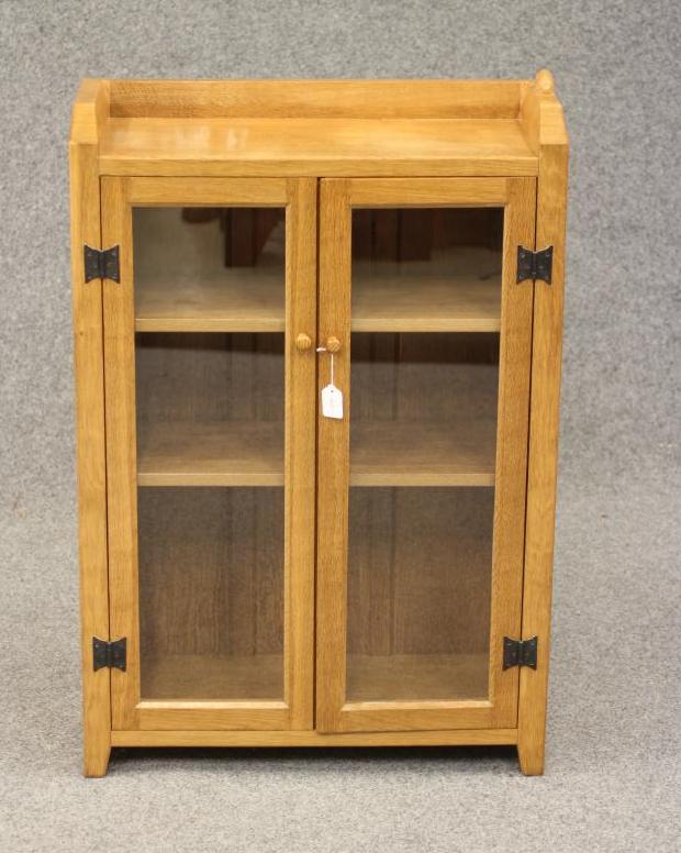 A PETER HEAP ADZED OAK BOOKCASE of shallow oblong form with a pair of glazed doors enclosing Image
