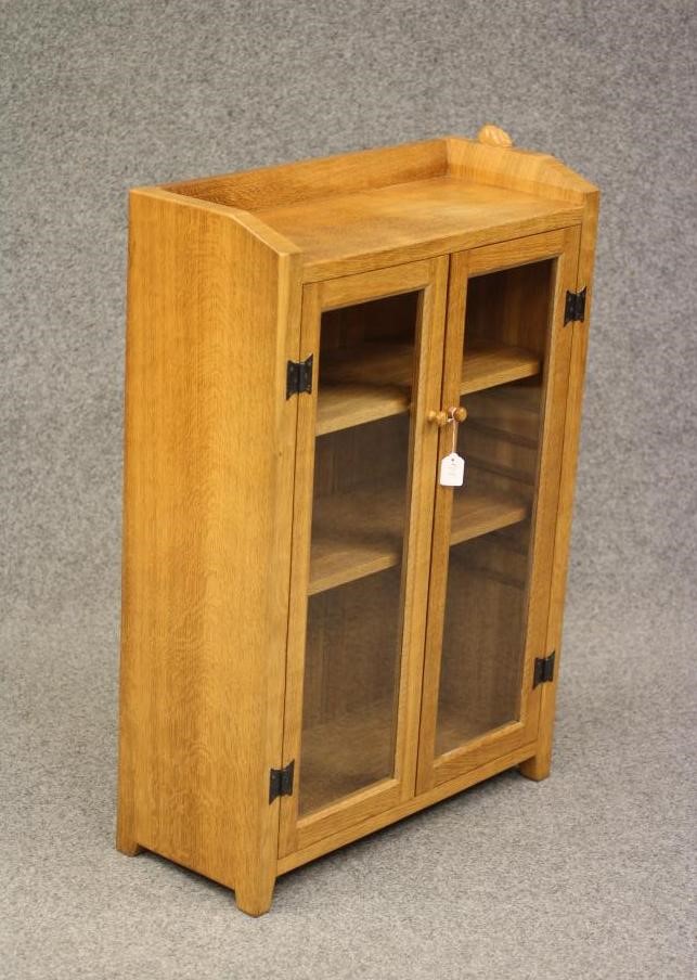 A PETER HEAP ADZED OAK BOOKCASE of shallow oblong form with a pair of glazed doors enclosing Image