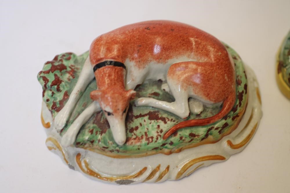 TWO LATE VICTORIAN STAFFORDSHIRE POTTERY MODELS OF RECUMBENT GREYHOUNDS Image