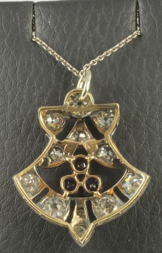 AN ART DECO DIAMOND AND SAPPHIRE PENDANT of stylised open anthemion form centred by three facet cut Image