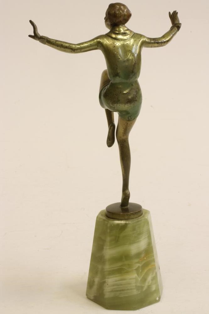 AN ART DECO COLD PAINTED BRONZE FIGURE of a young lady standing on her right leg with arms Image