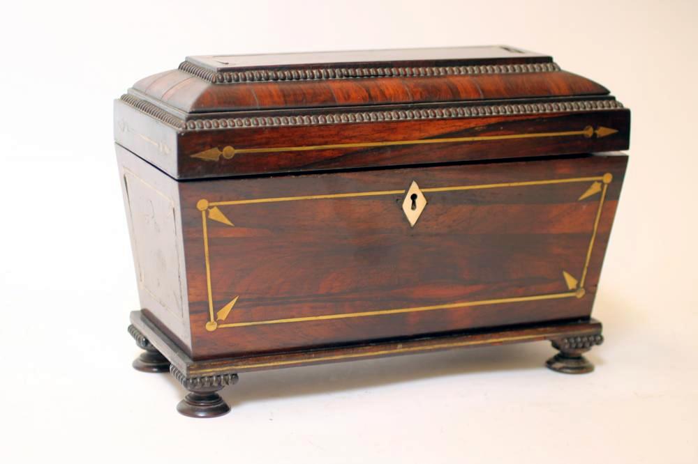 A REGENCY ROSEWOOD TEA CHEST of sarcophagus form with brass stringing and reel edging Image