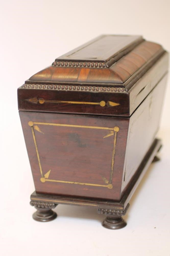 A REGENCY ROSEWOOD TEA CHEST of sarcophagus form with brass stringing and reel edging Image
