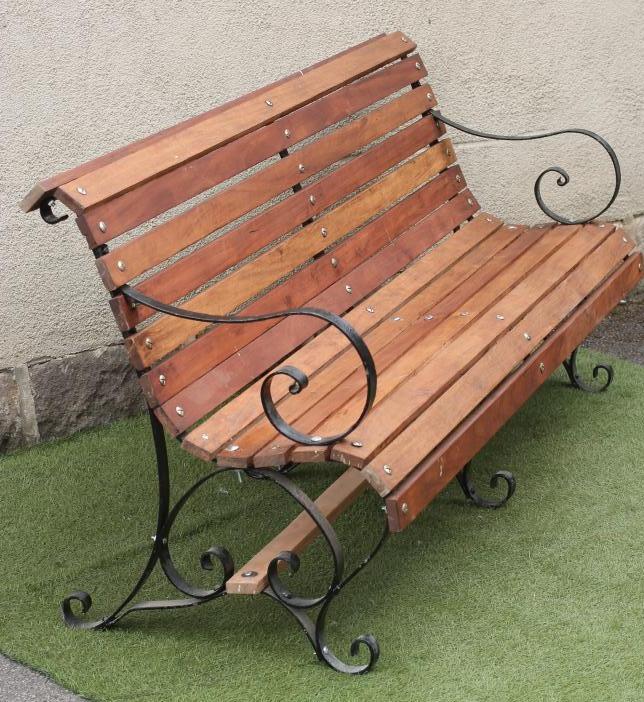 A VICTORIAN PARK BENCH of scroll back form with hard wood slatted back and seat Image