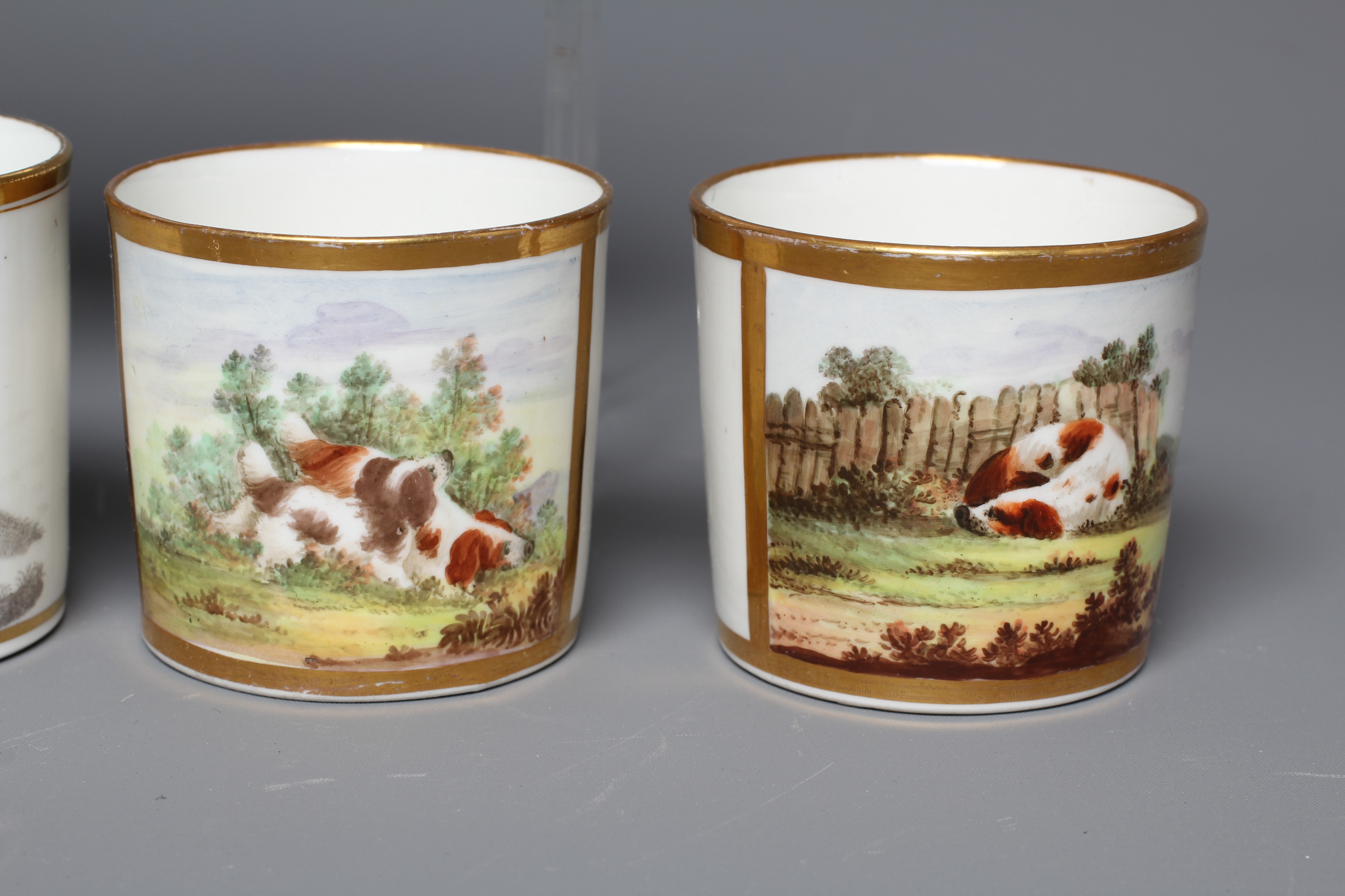 A SET OF THREE ENGLISH PORCELAIN COFFEE CANS painted in polychrome enamels with a gilt square panel Image