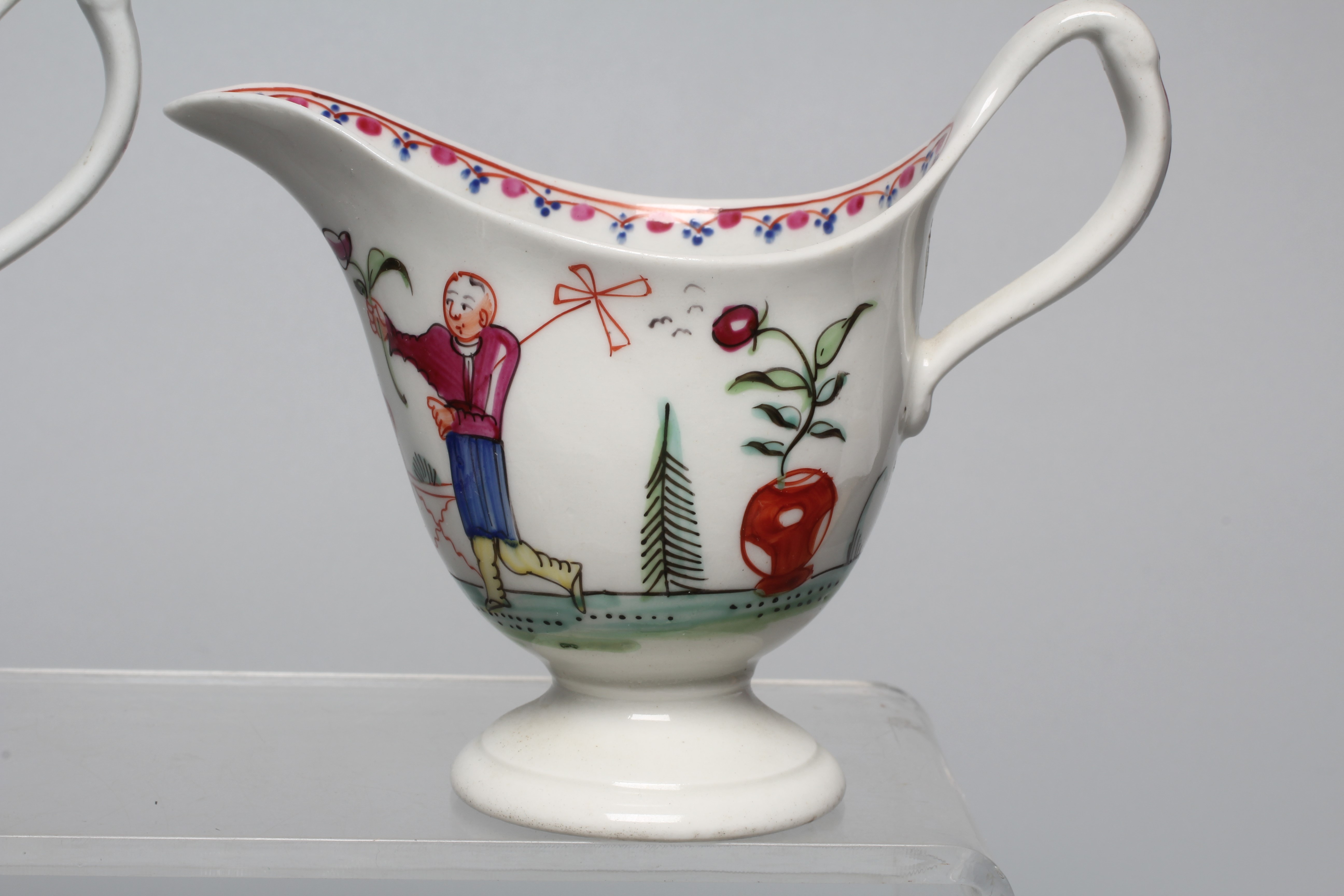 TWO NEWHALL PORCELAIN HELMET CREAM JUGS both with clip handles and painted in polychrome enamels Image