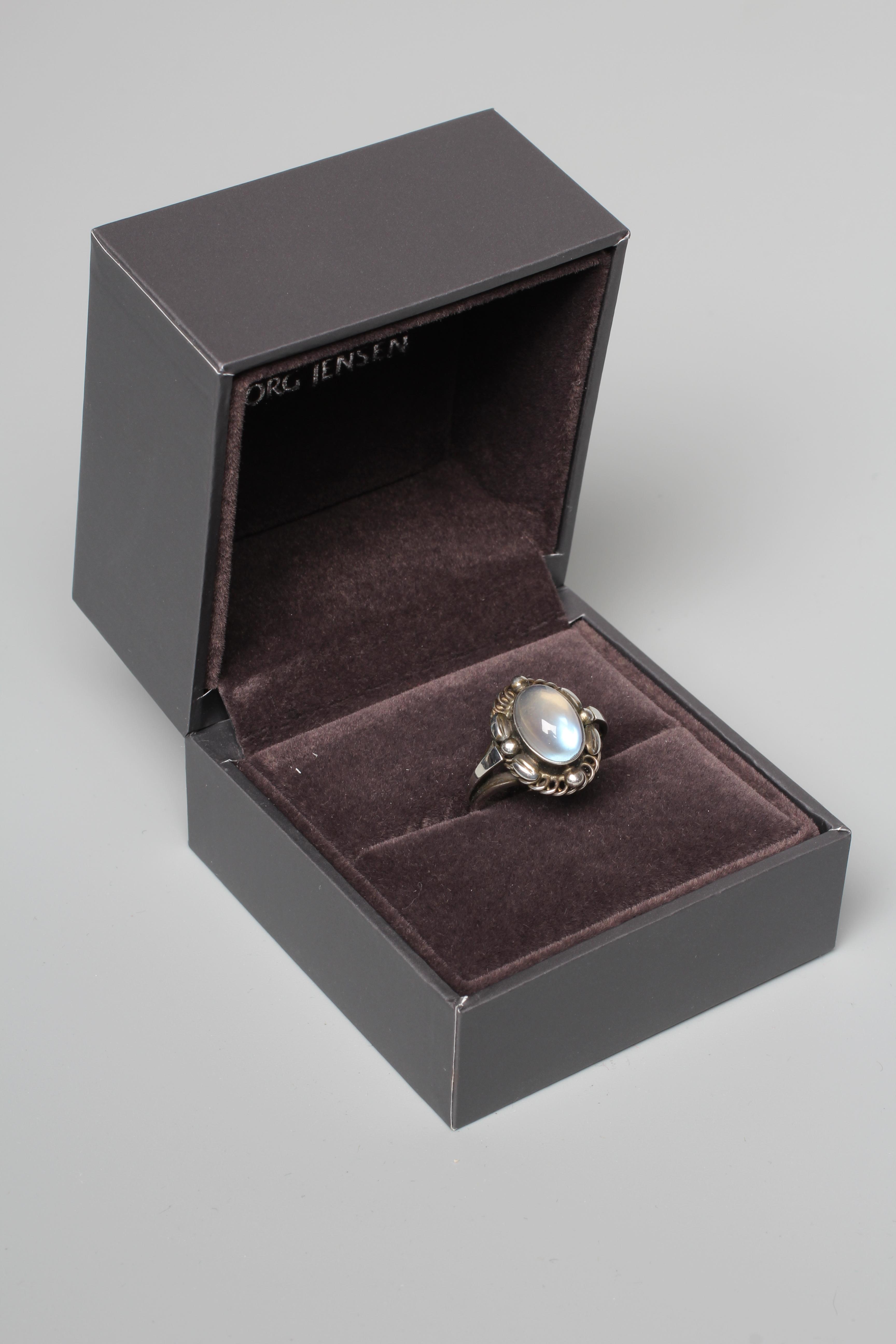 A GEORG JENSEN SILVER SEED AND POD RING collet set with an oval polished moonstone cabochon, stamped Image