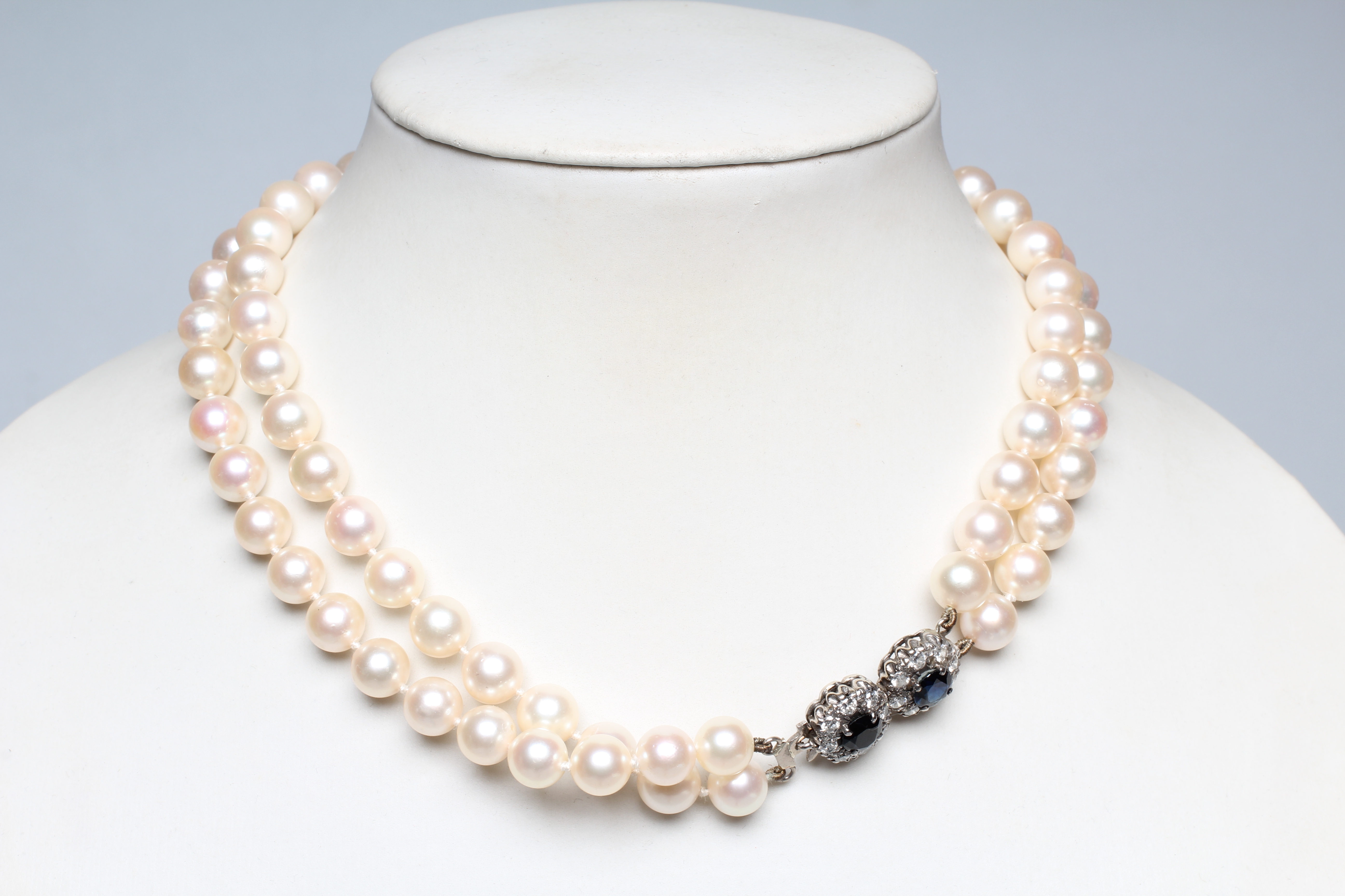A DOUBLE STRAND CULTURED PEARL CHOKER, set to an unmarked white metal clasp with two sapphire and Image