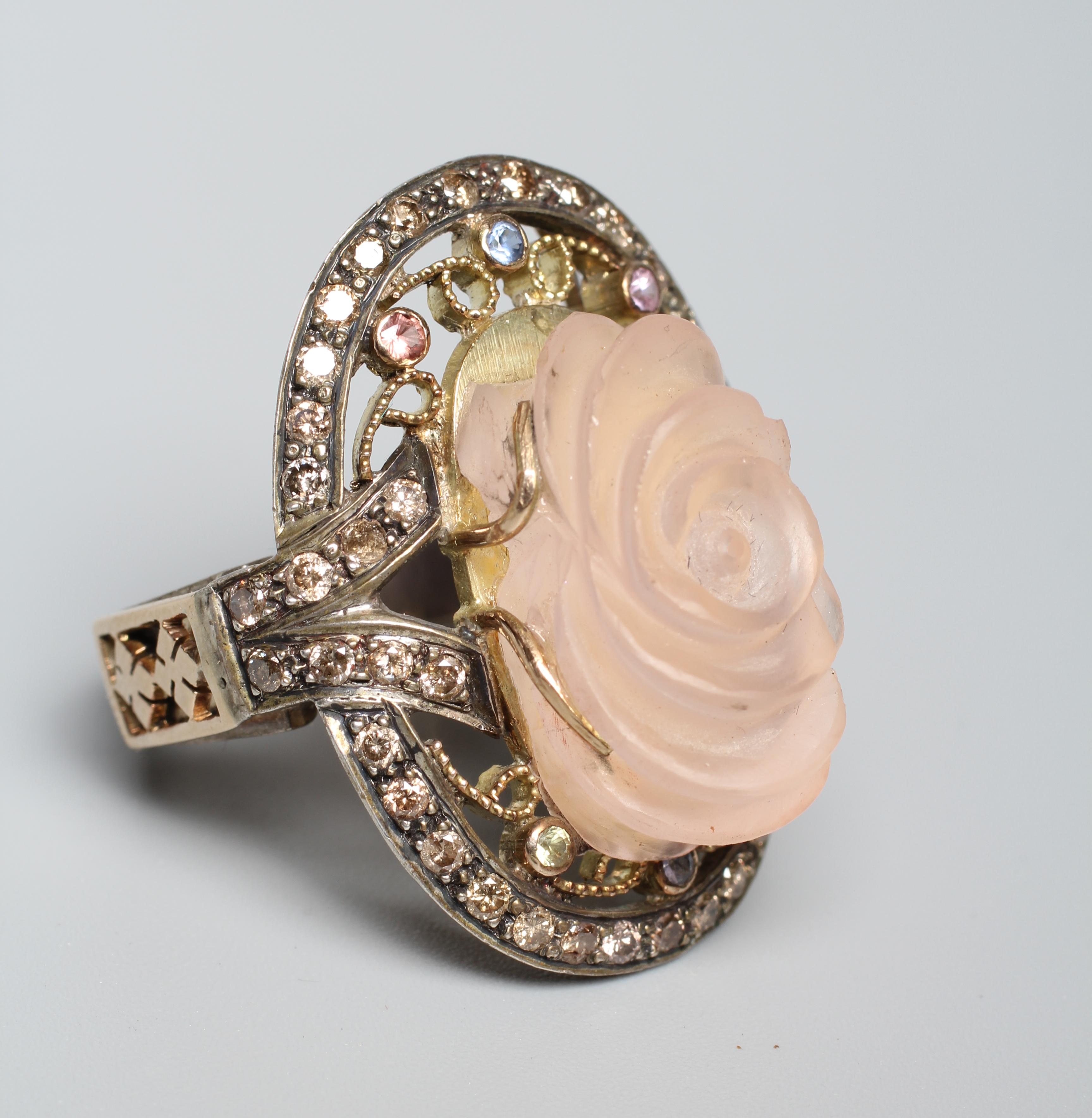 A ROSE QUARTZ COCKTAIL RING, the oval rose head cut stone claw set to an open surround with white Image