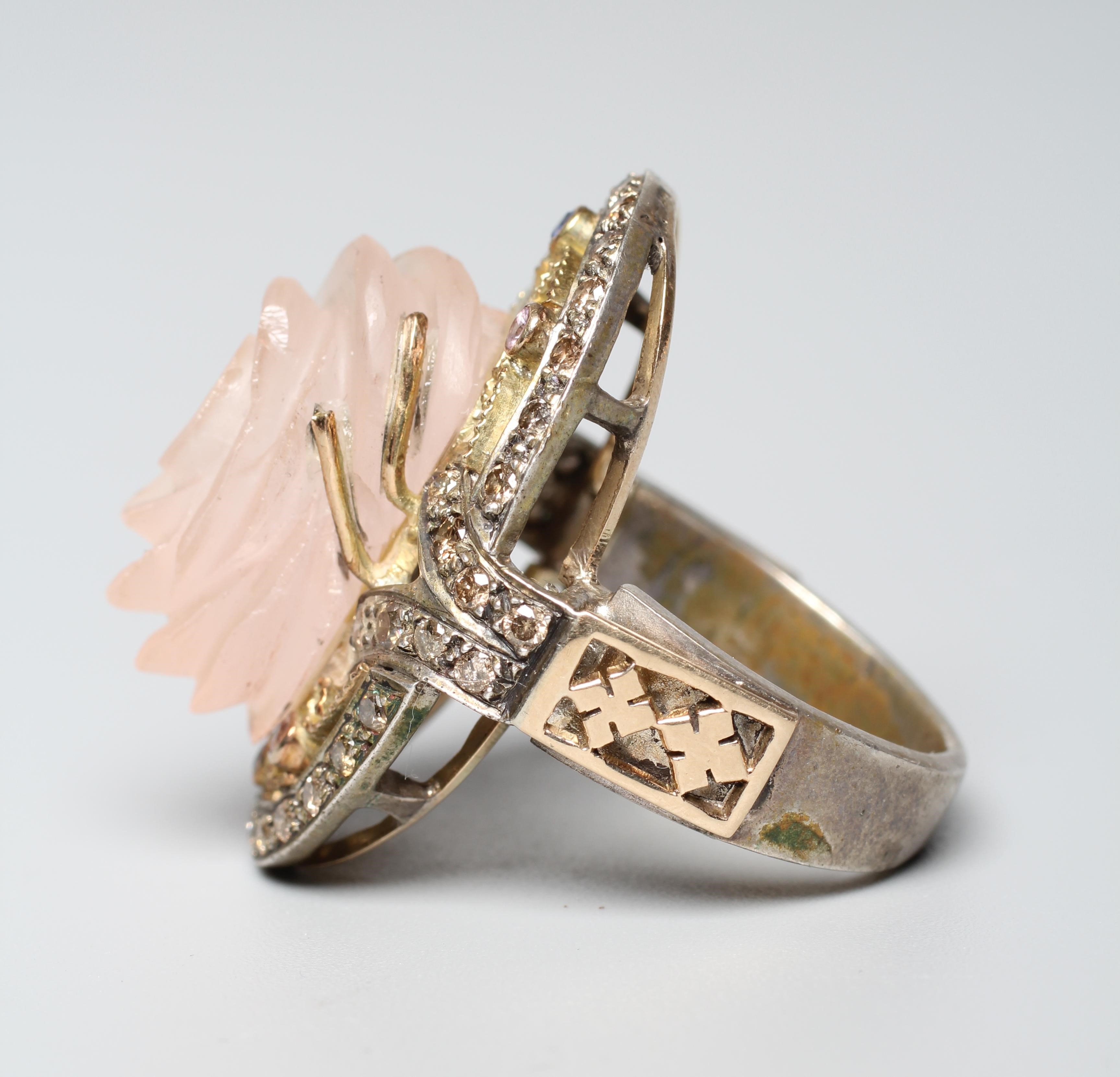 A ROSE QUARTZ COCKTAIL RING, the oval rose head cut stone claw set to an open surround with white Image