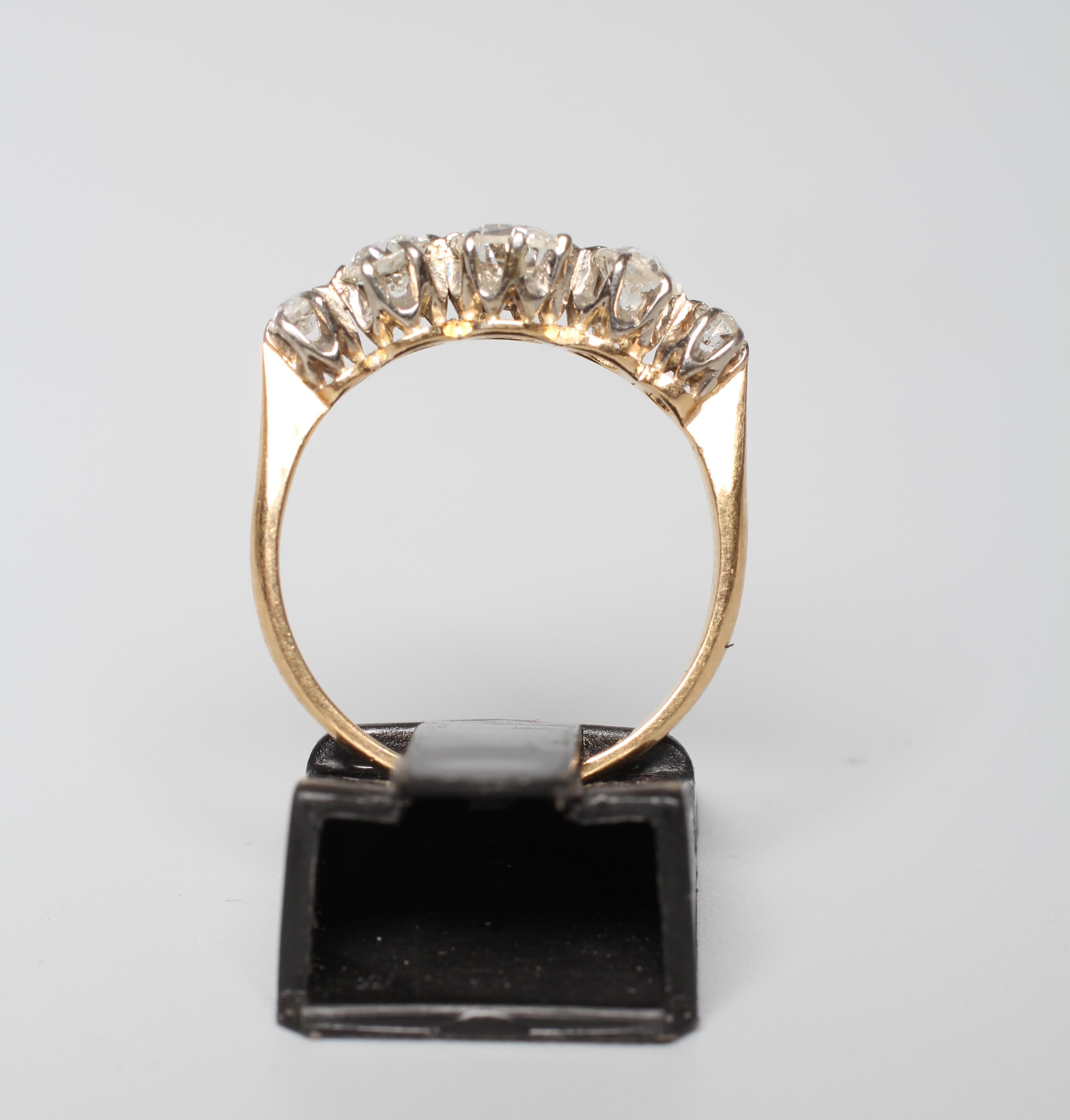 A FIVE STONE DIAMOND RING, the graduating brilliant cut stones claw set to a plain unmarked shank, Image