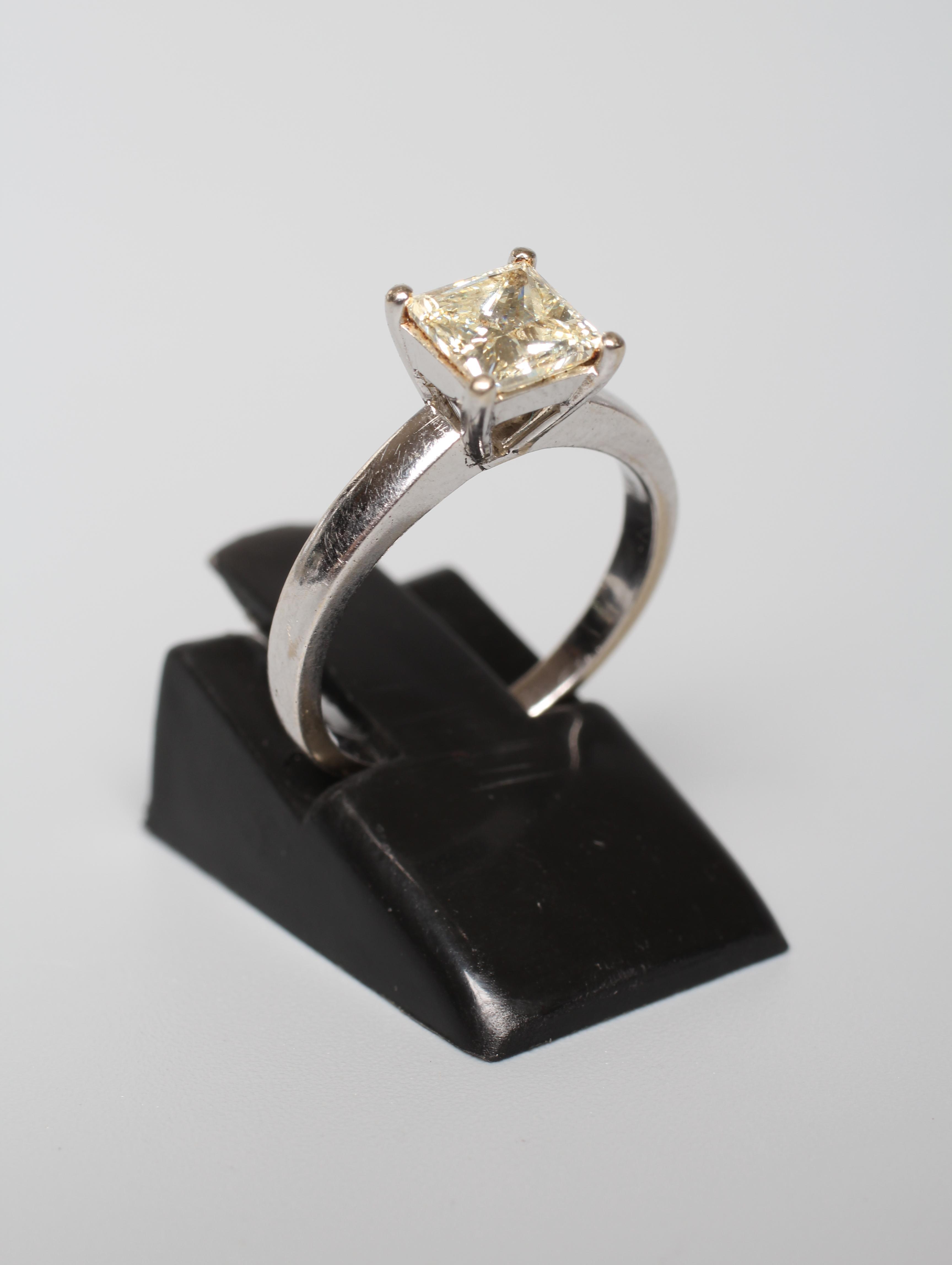 A SOLITAIRE DIAMOND RING, the Princess cut stone of approximately 1ct, claw set to a plain white Image