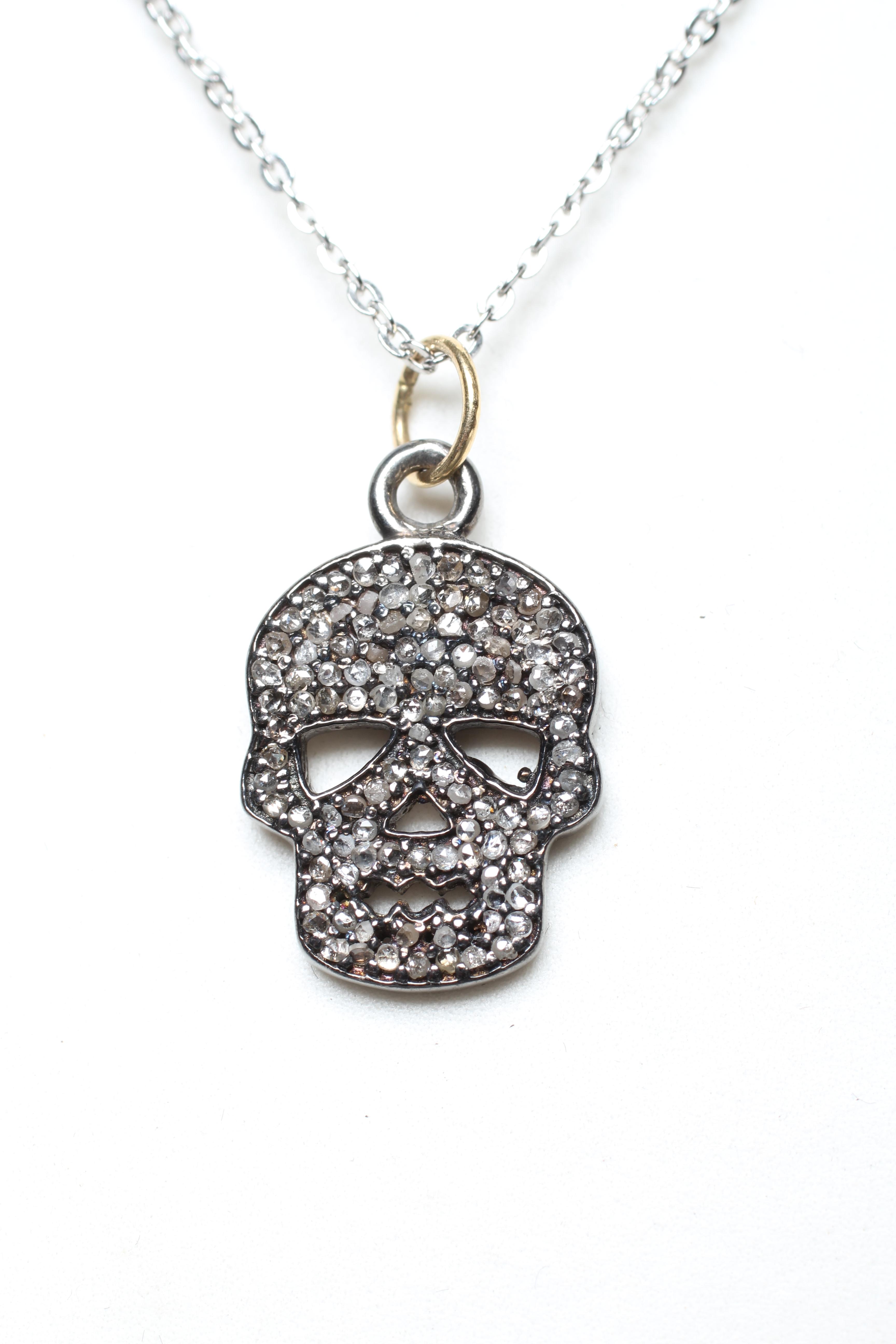 A DIAMOND SKULL PENDANT, the numerous rose cut stones pave set to a silver mount, on a silver chain Image