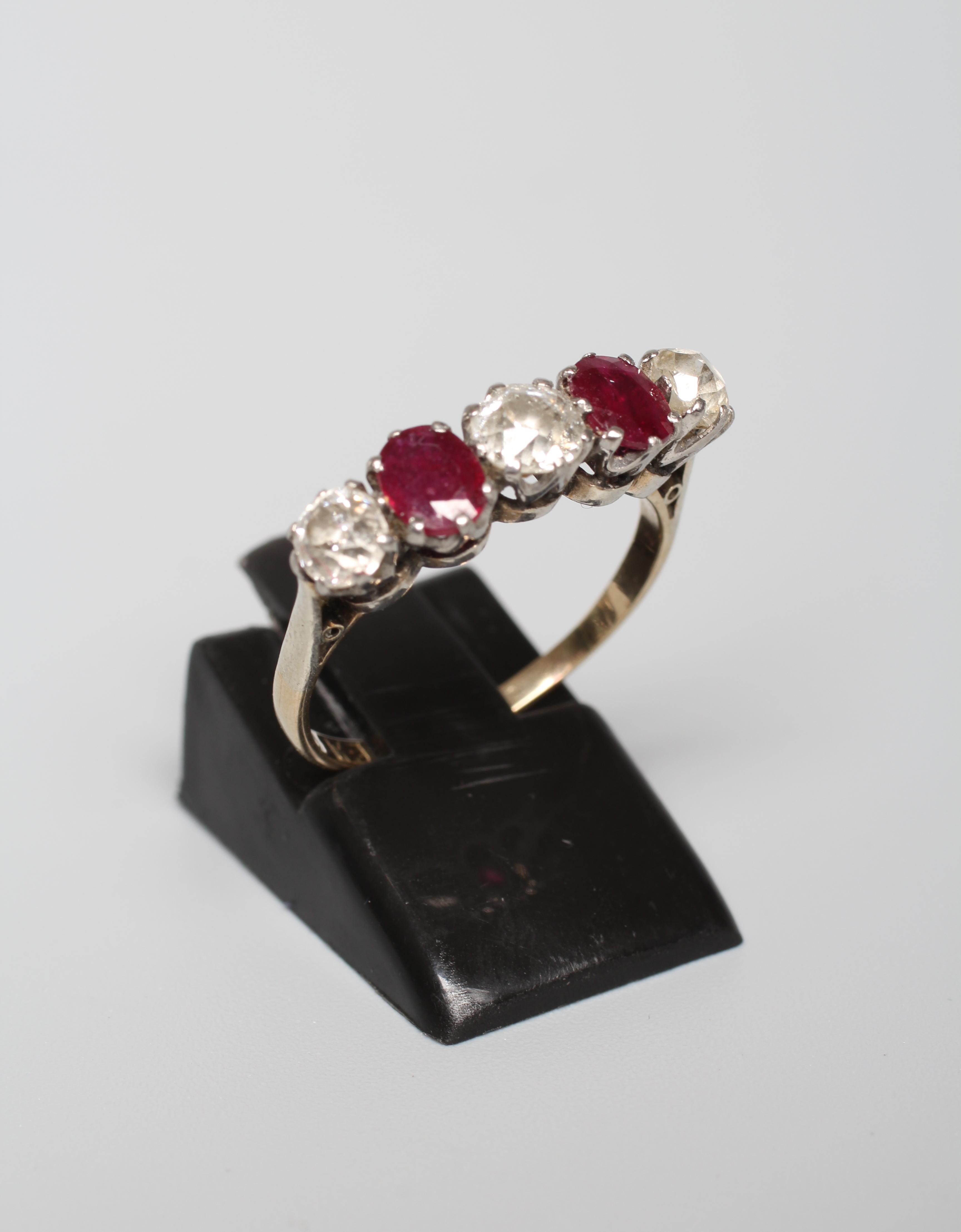 A RUBY AND DIAMOND FIVE STONE RING, the two oval facet cut rubies claw set with three graduating mix Image