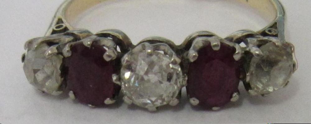 A RUBY AND DIAMOND FIVE STONE RING, the two oval facet cut rubies claw set with three graduating mix Image
