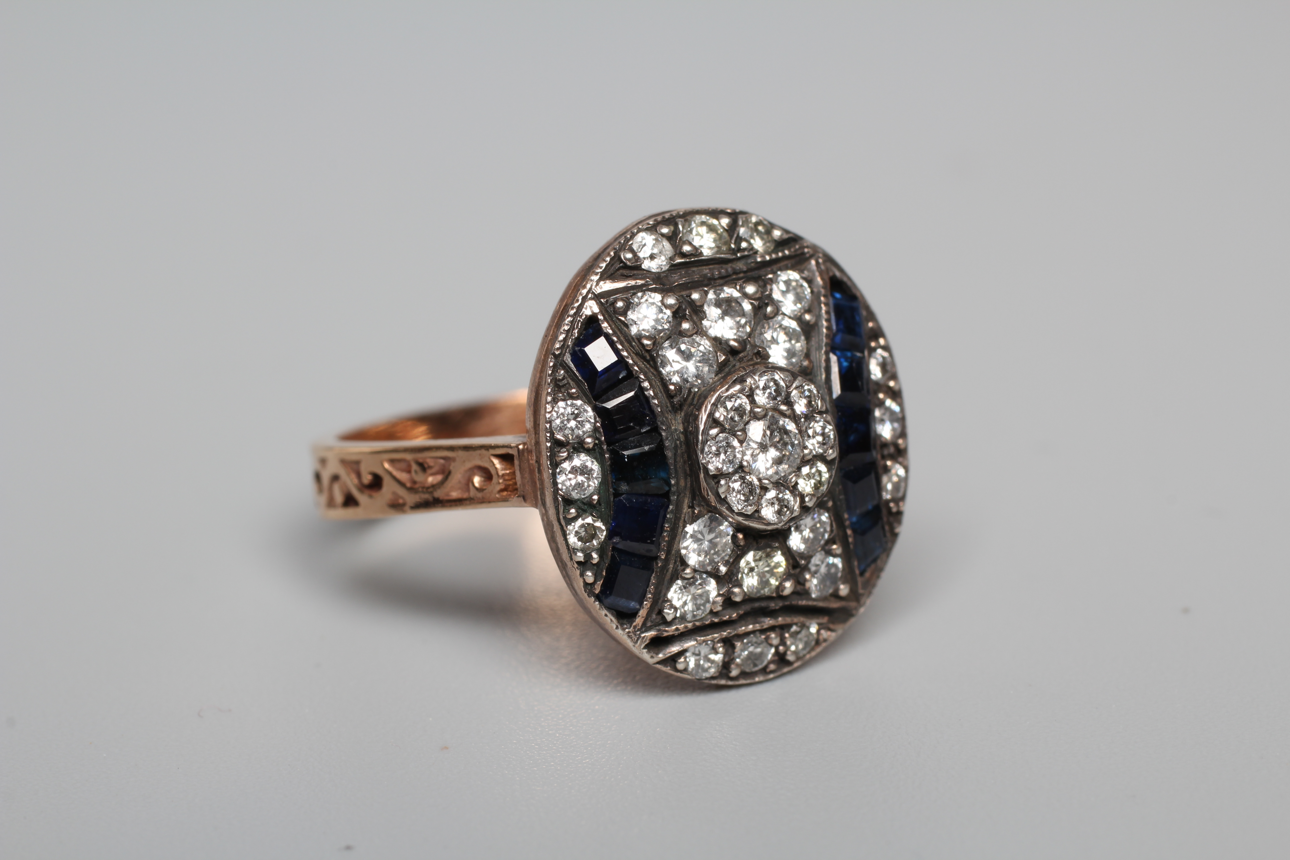 AN ART DECO STYLE SAPPHIRE AND DIAMOND RING, the oval silver panel set with calibre cut sapphires Image