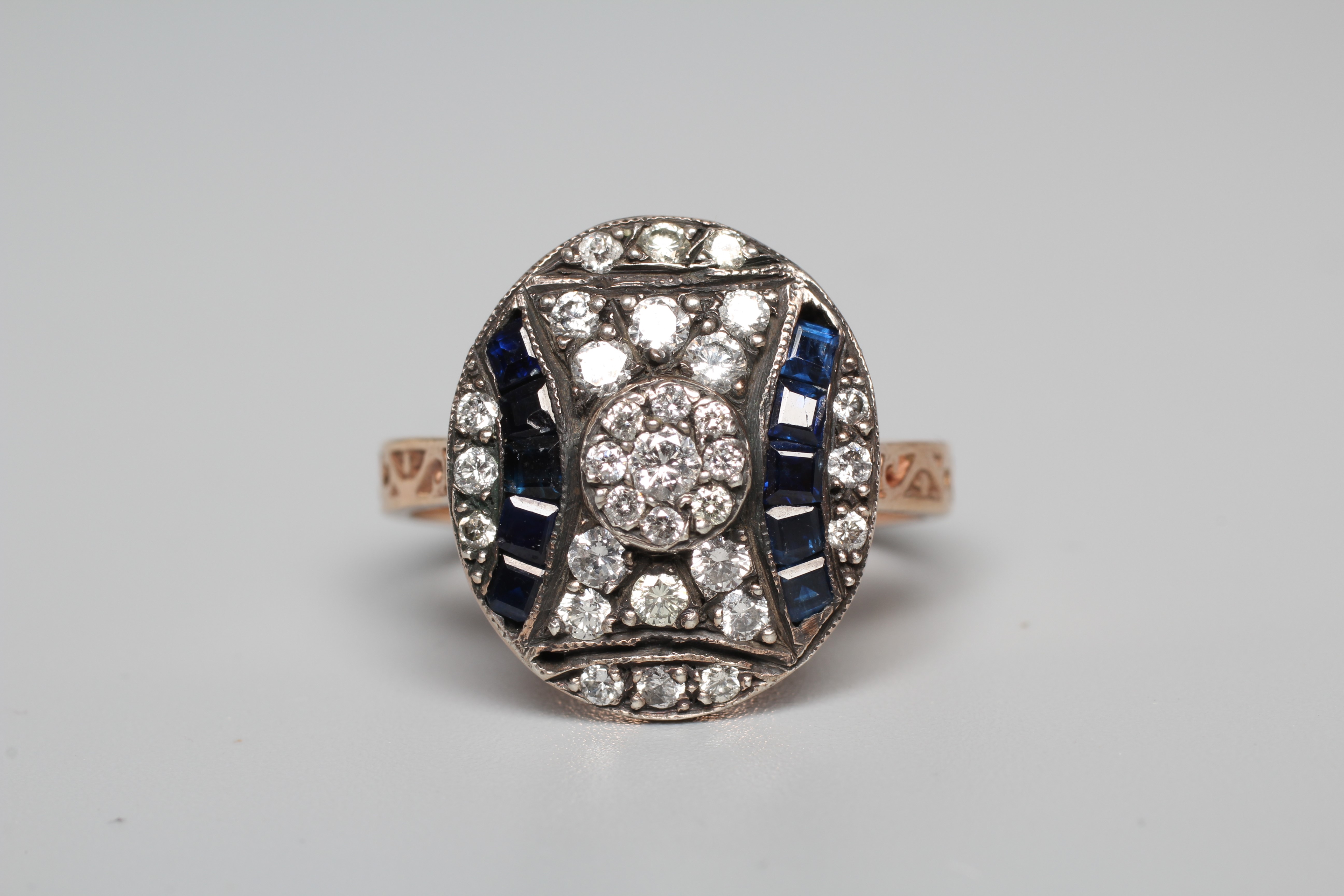 AN ART DECO STYLE SAPPHIRE AND DIAMOND RING, the oval silver panel set with calibre cut sapphires Image