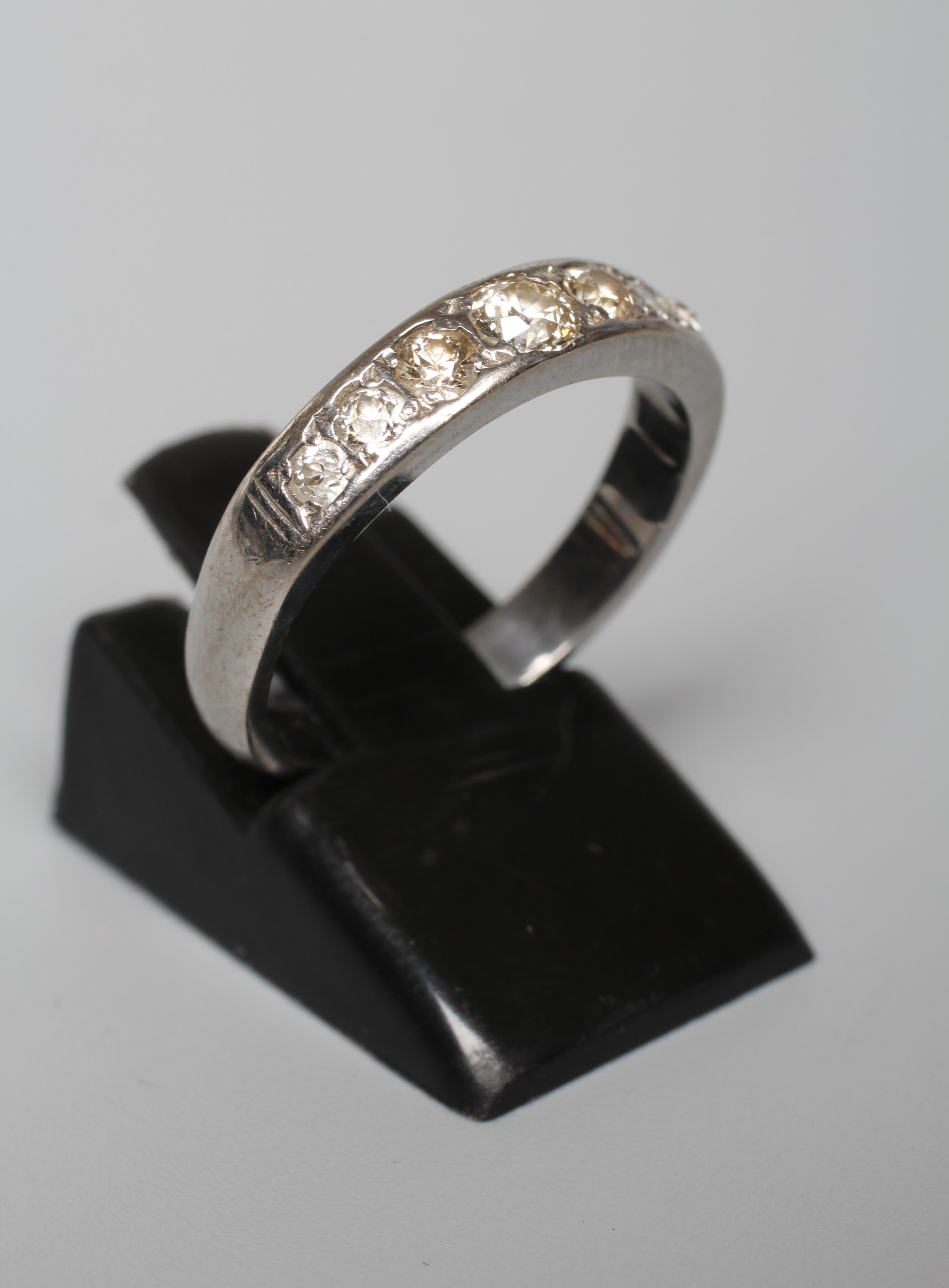 A SEVEN STONE DIAMOND HALF HOOP ETERNITY RING, the graduating stones in rub over setting to a plain Image