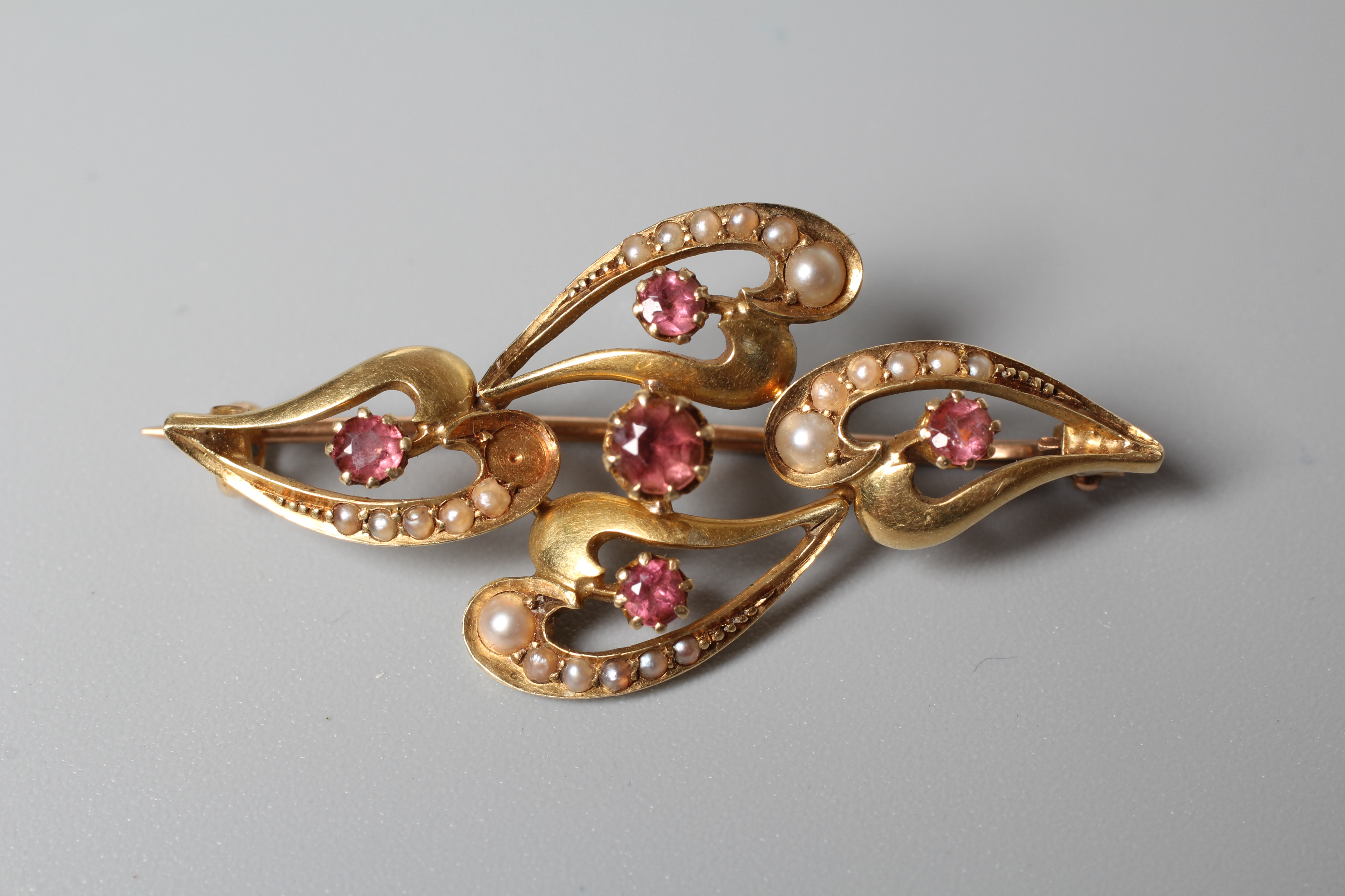 AN EDWARDIAN BROOCH stamped 15ct, the four elongated open hearts part pave set with graduating seed Image