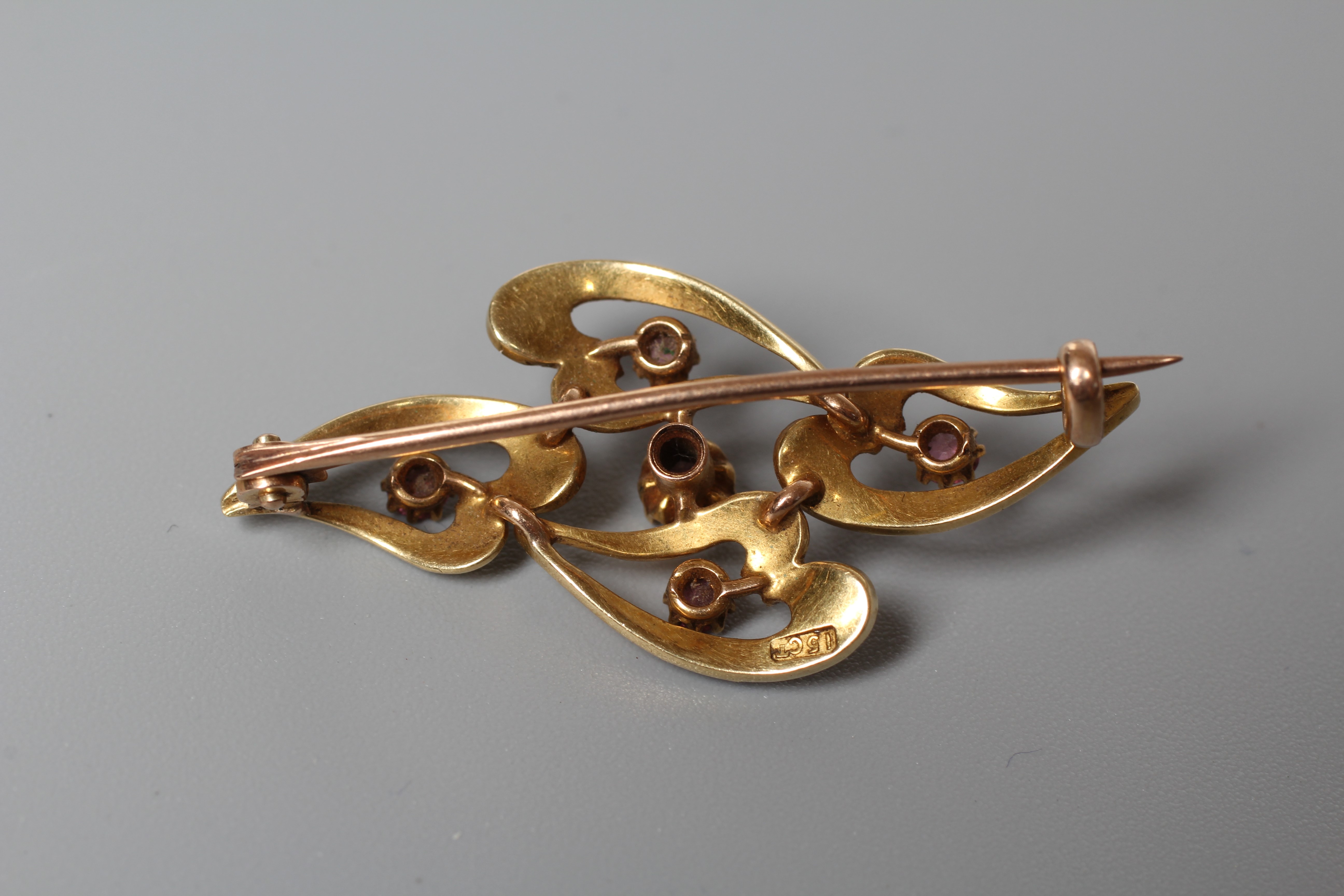 AN EDWARDIAN BROOCH stamped 15ct, the four elongated open hearts part pave set with graduating seed Image