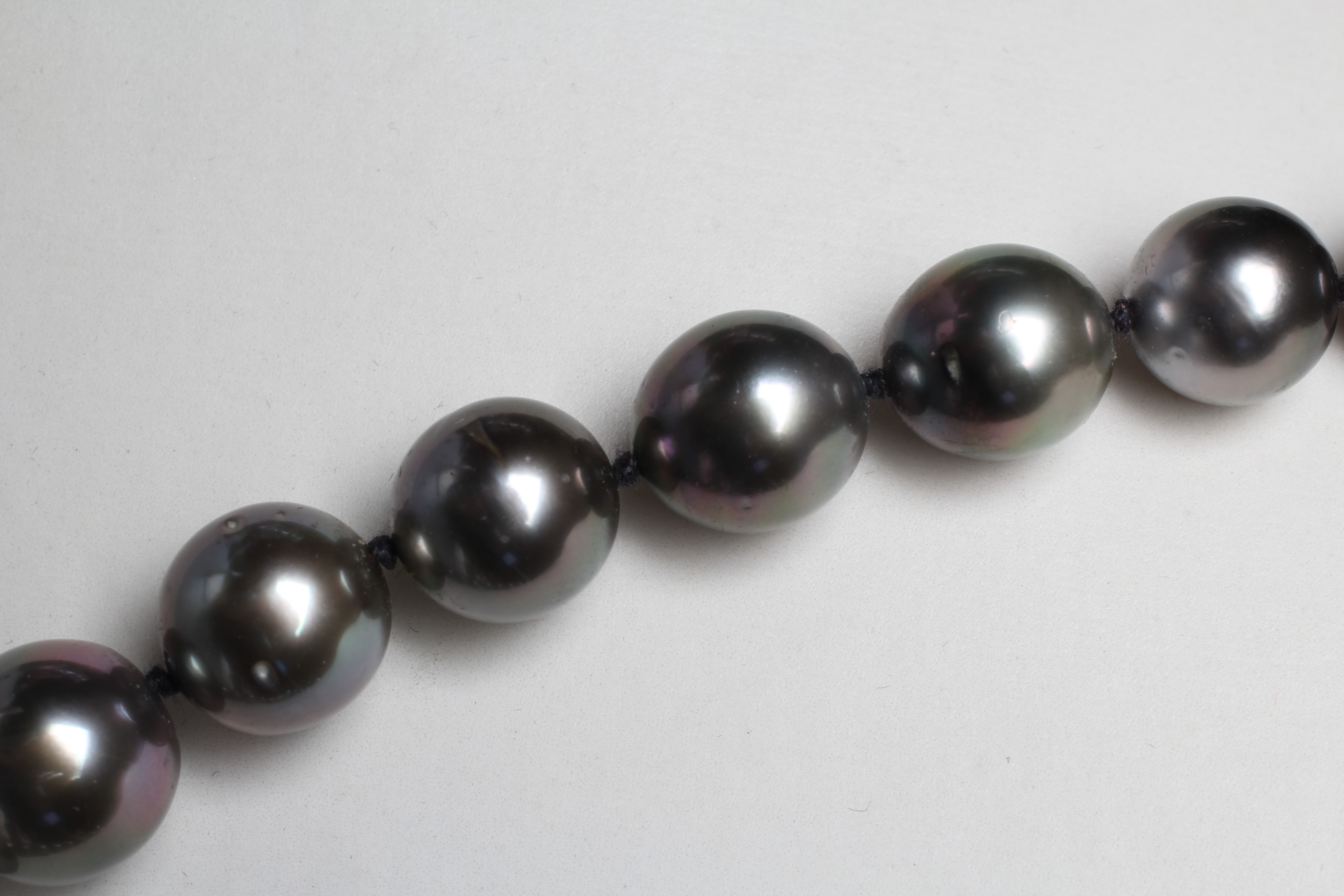 A SINGLE STRING OF BLACK TAHITIAN CULTURED PEARLS, the thirty six pearls with a white ball clasp Image