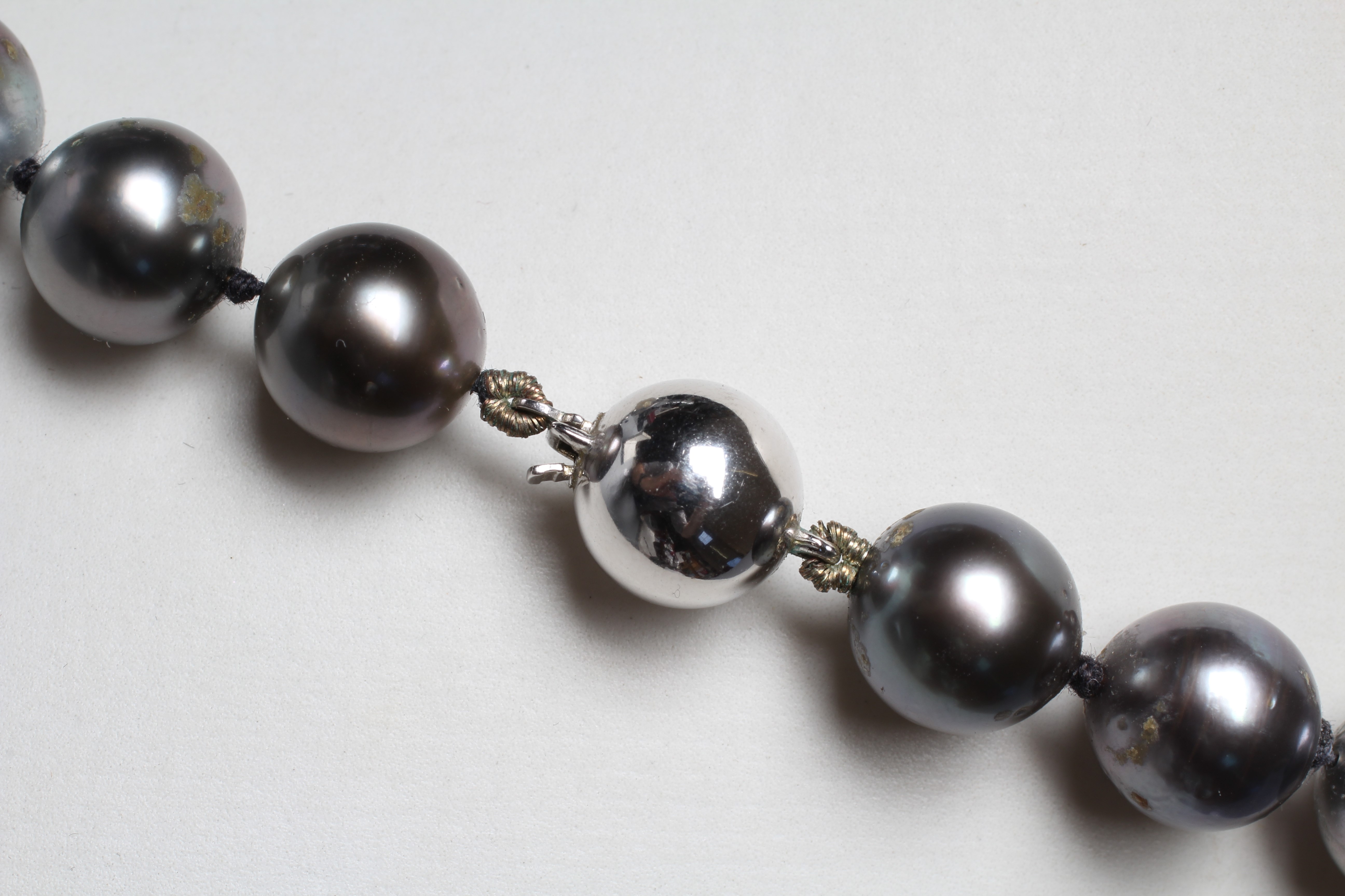 A SINGLE STRING OF BLACK TAHITIAN CULTURED PEARLS, the thirty six pearls with a white ball clasp Image