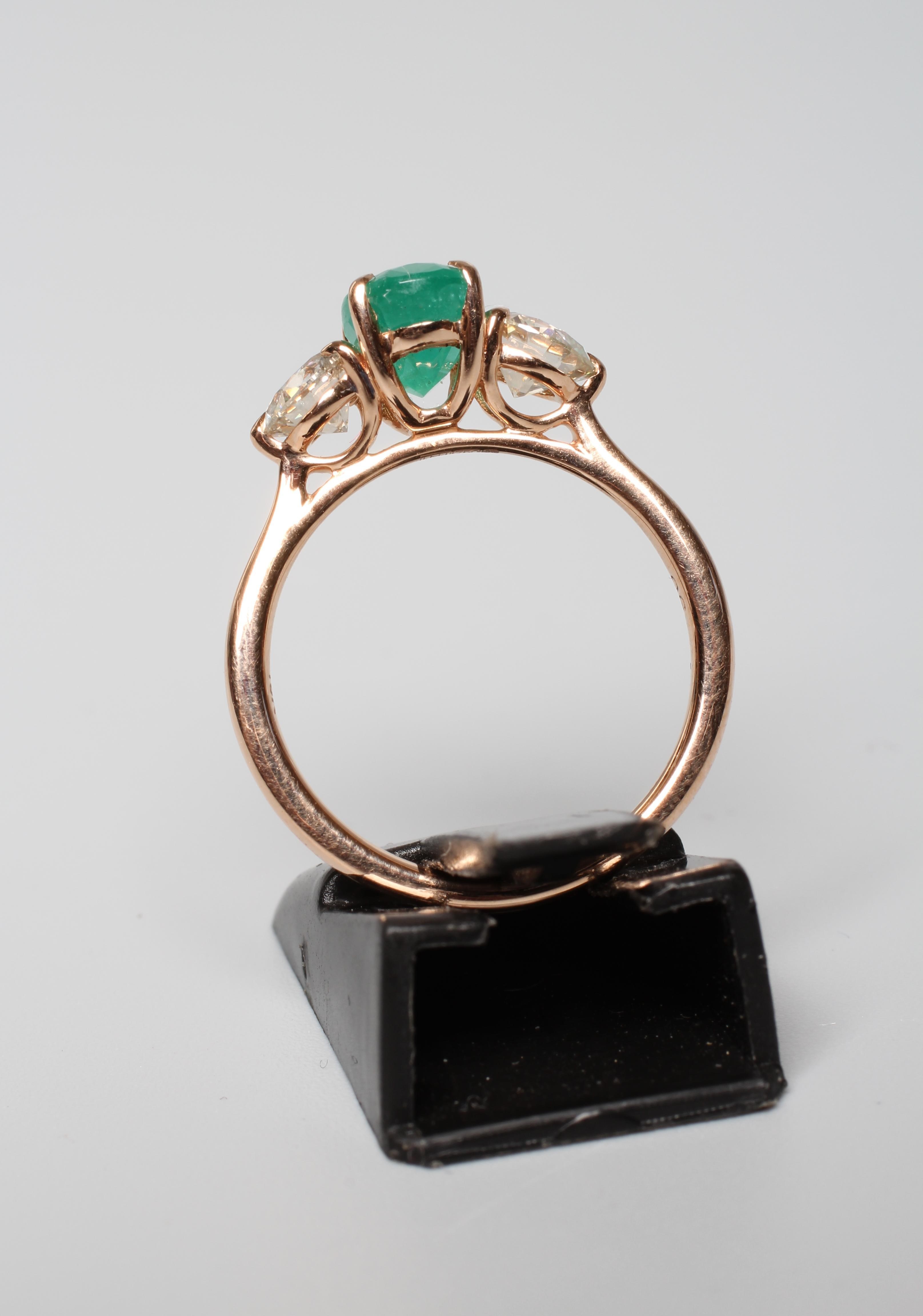 AN EMERALD AND DIAMOND RING, the oval facet cut emerald claw set and flanked by two round brilliant Image