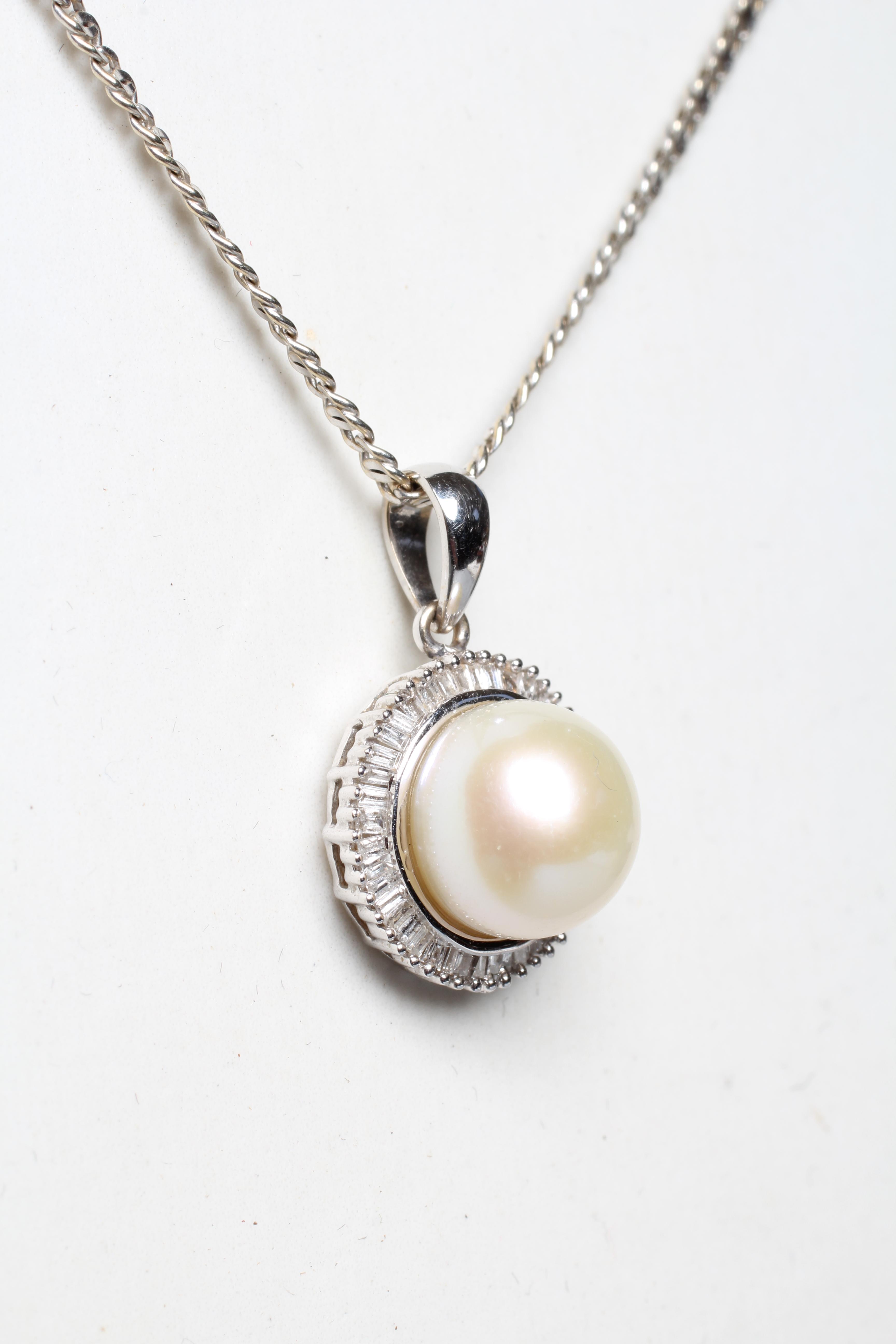 A CULTURED PEARL AND DIAMOND PENDANT, the peg set pearl within a border of small baguette cut Image