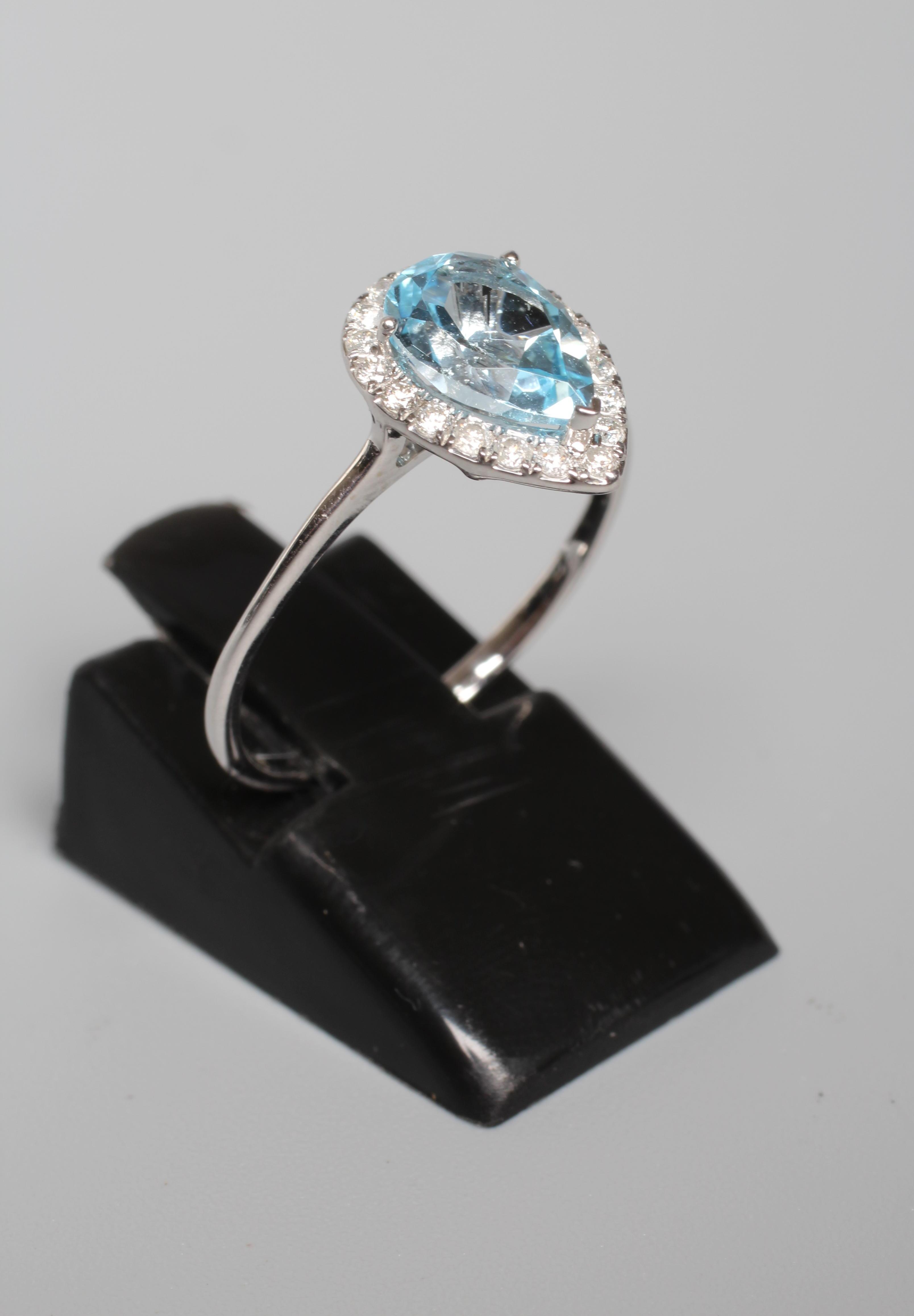 A BLUE TOPAZ AND DIAMOND CLUSTER RING, the pear shaped facet cut topaz claw set to a border of Image