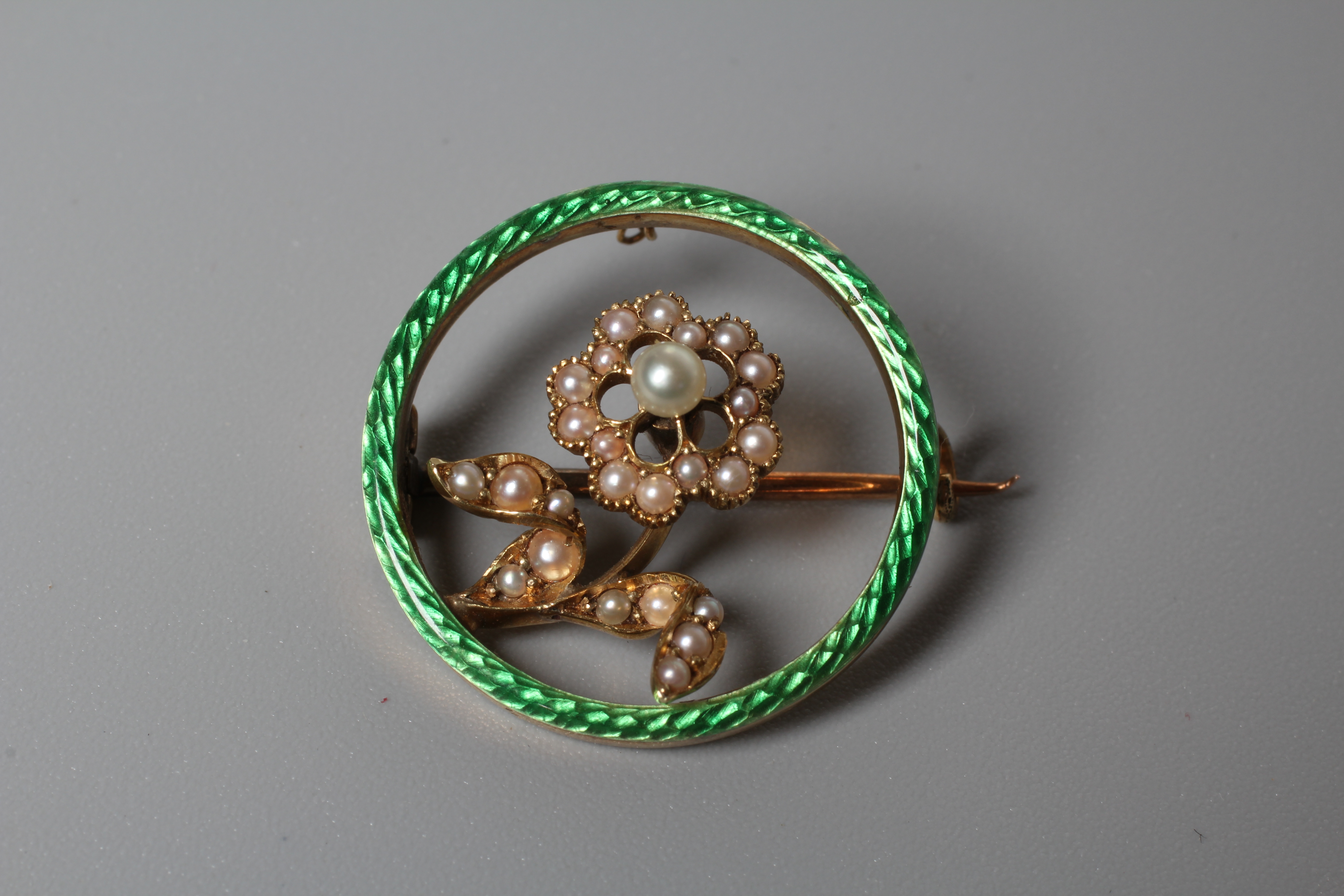 AN EDWARDIAN FLOWER BROOCH centred by a seed pearl set flower on a knife edge bar and an outer green Image