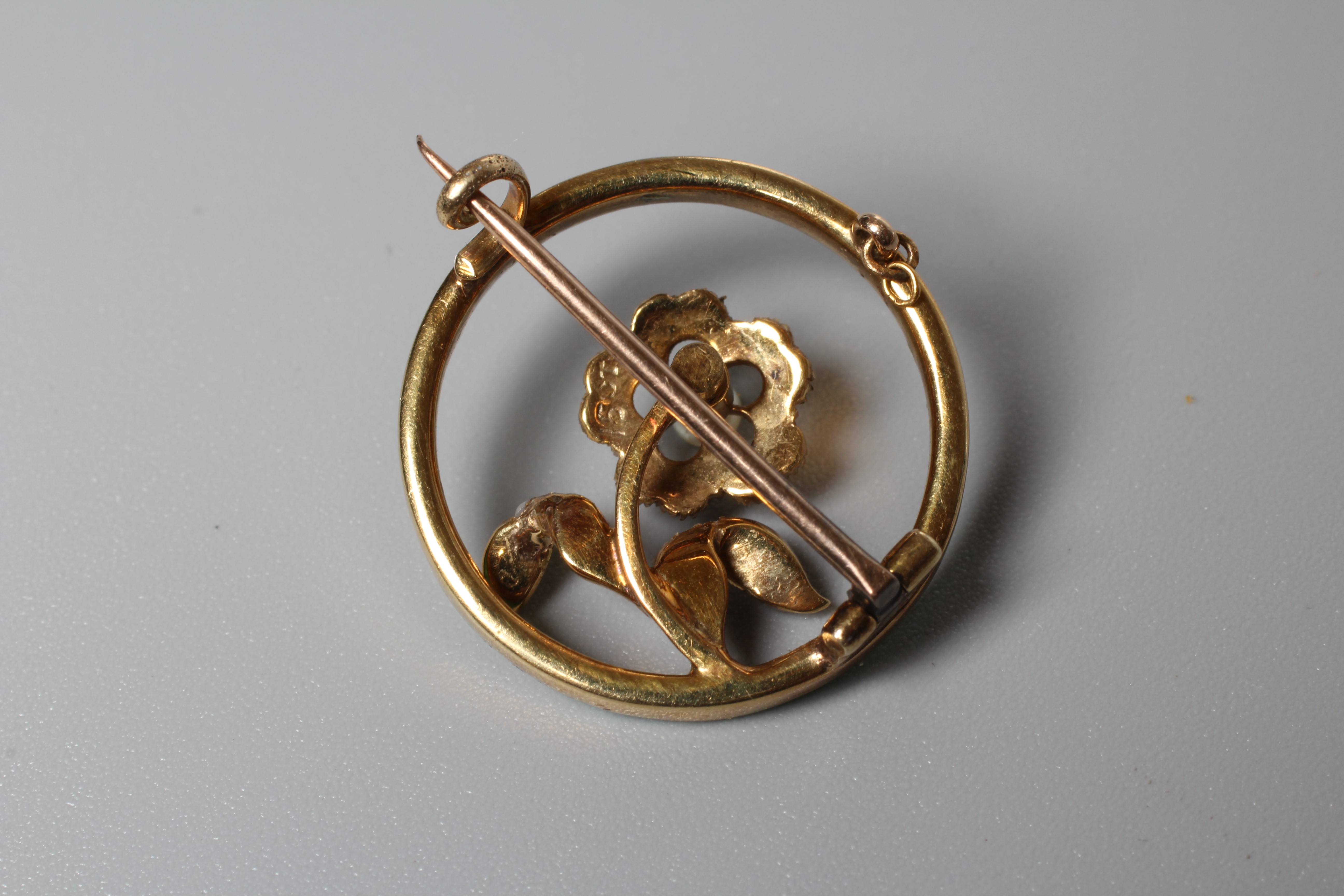 AN EDWARDIAN FLOWER BROOCH centred by a seed pearl set flower on a knife edge bar and an outer green Image