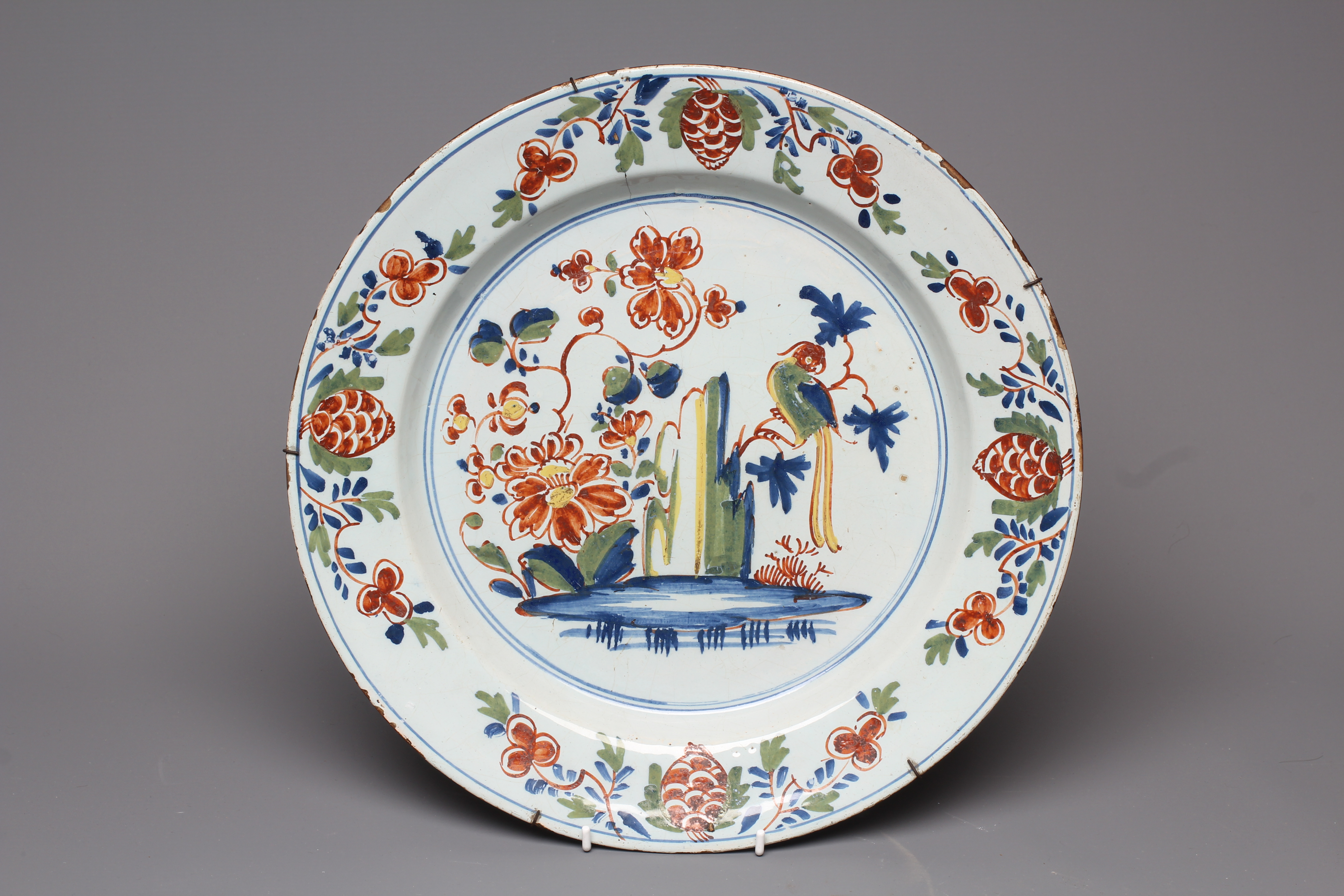 A LAMBETH DELFT CHARGER, c.1760, painted in blue, ochre, green and burnt orange with a large parrot Image
