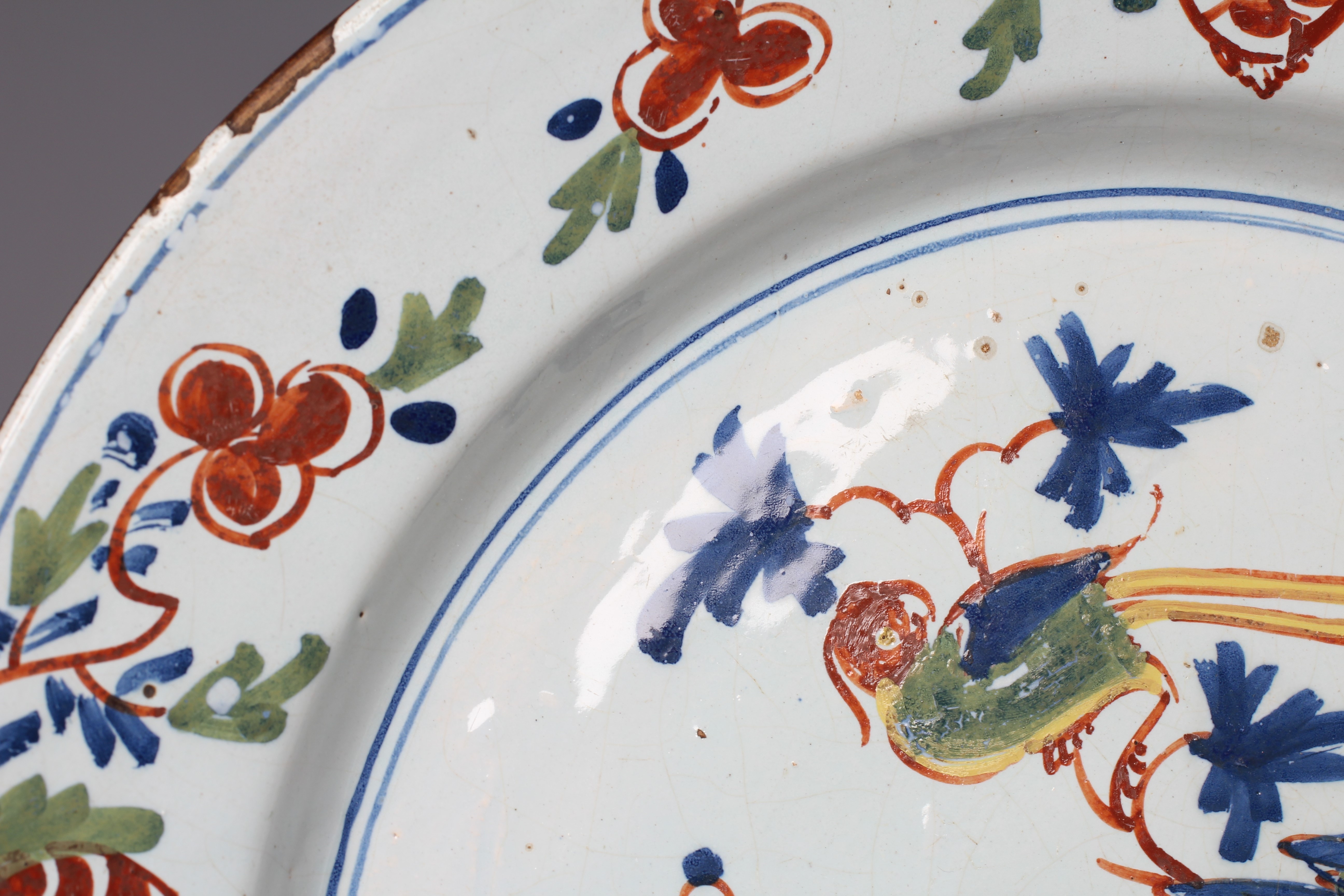 A LAMBETH DELFT CHARGER, c.1760, painted in blue, ochre, green and burnt orange with a large parrot Image