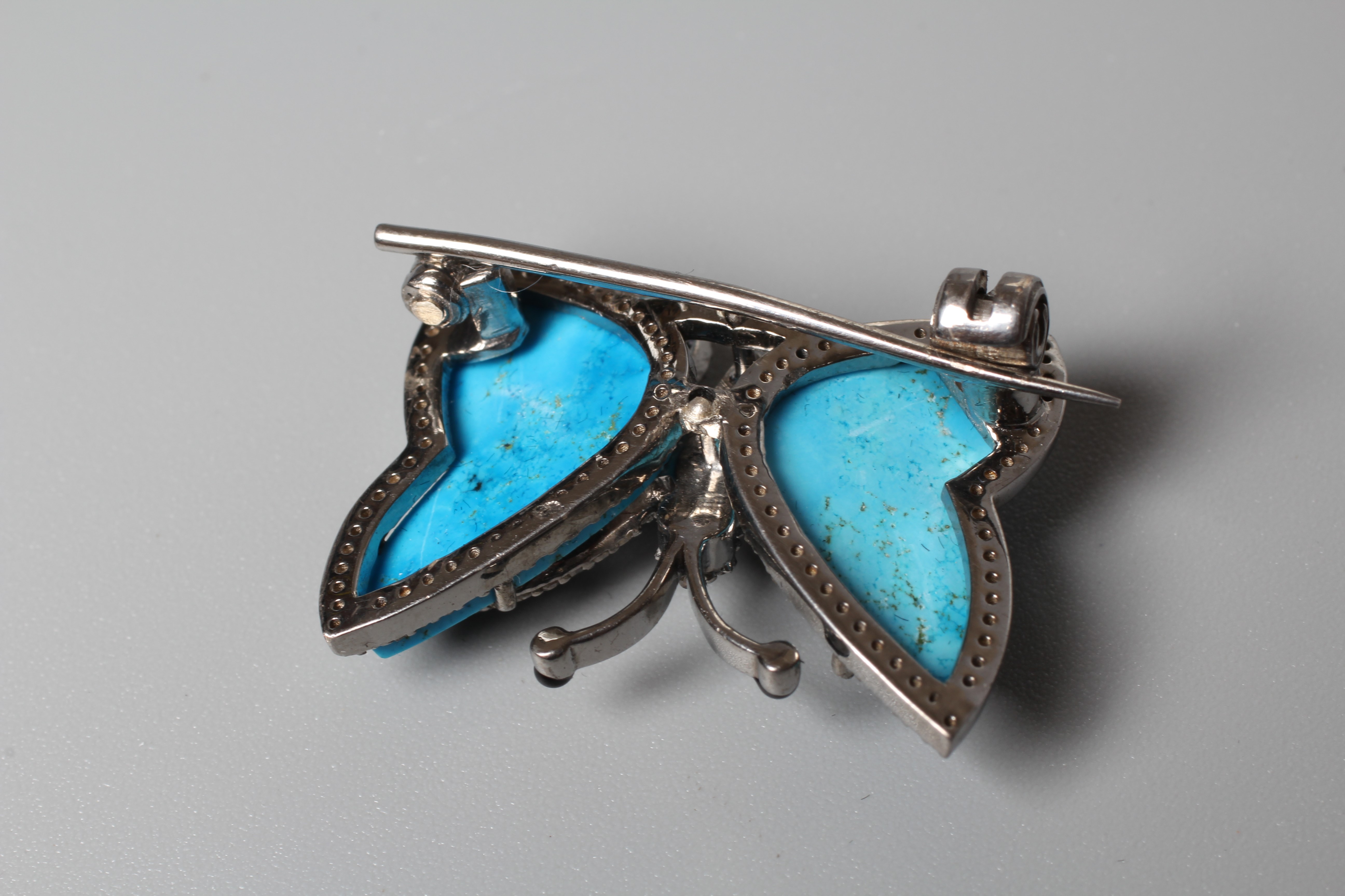 A BUTTERFLY BROOCH, the unmarked silver frame inset with turquoise wings with black enamel tips and Image
