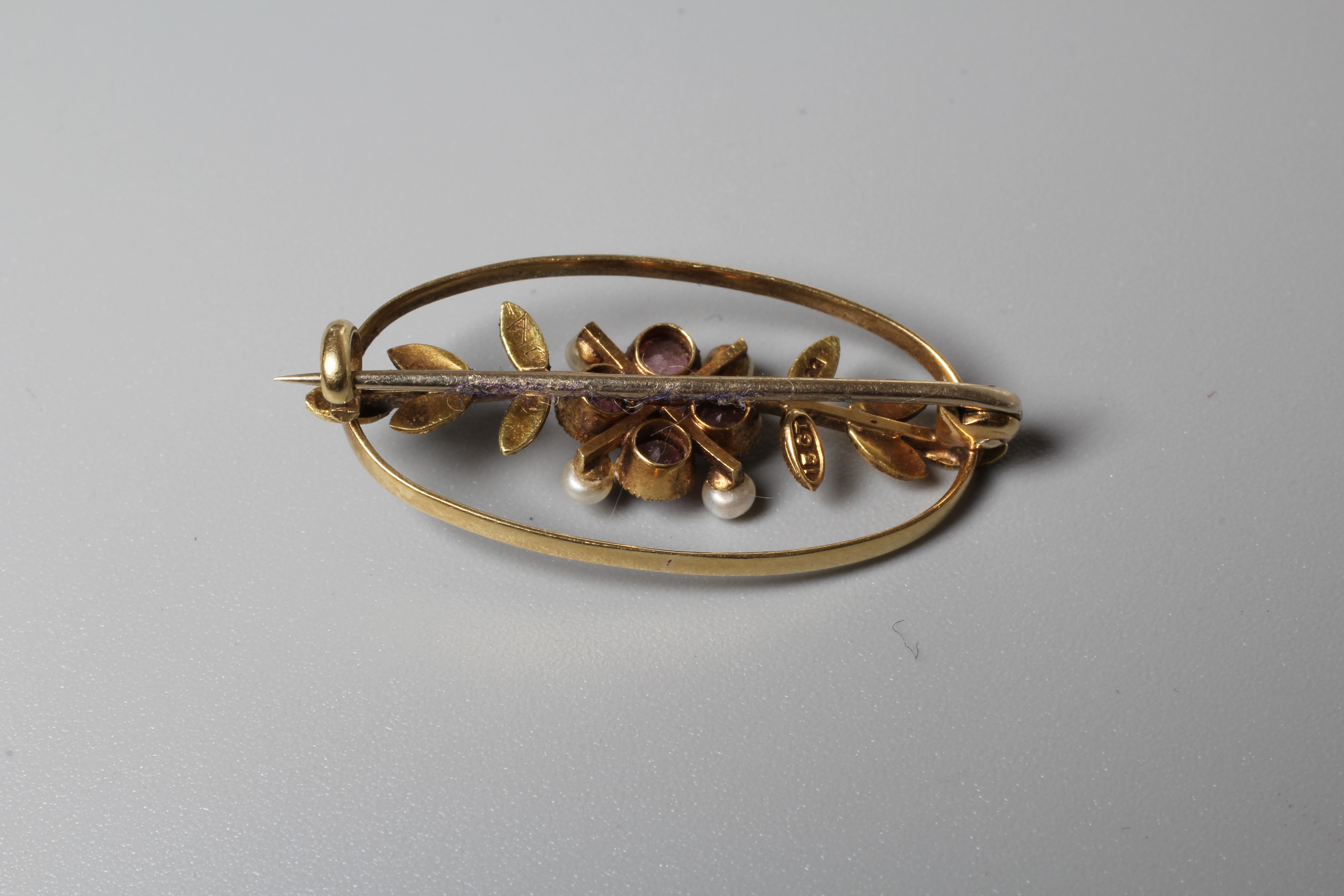 AN EDWARDIAN ALMANDINE GARNET OVAL BROOCH, the open panel centred by a garnet set flowerhead with Image