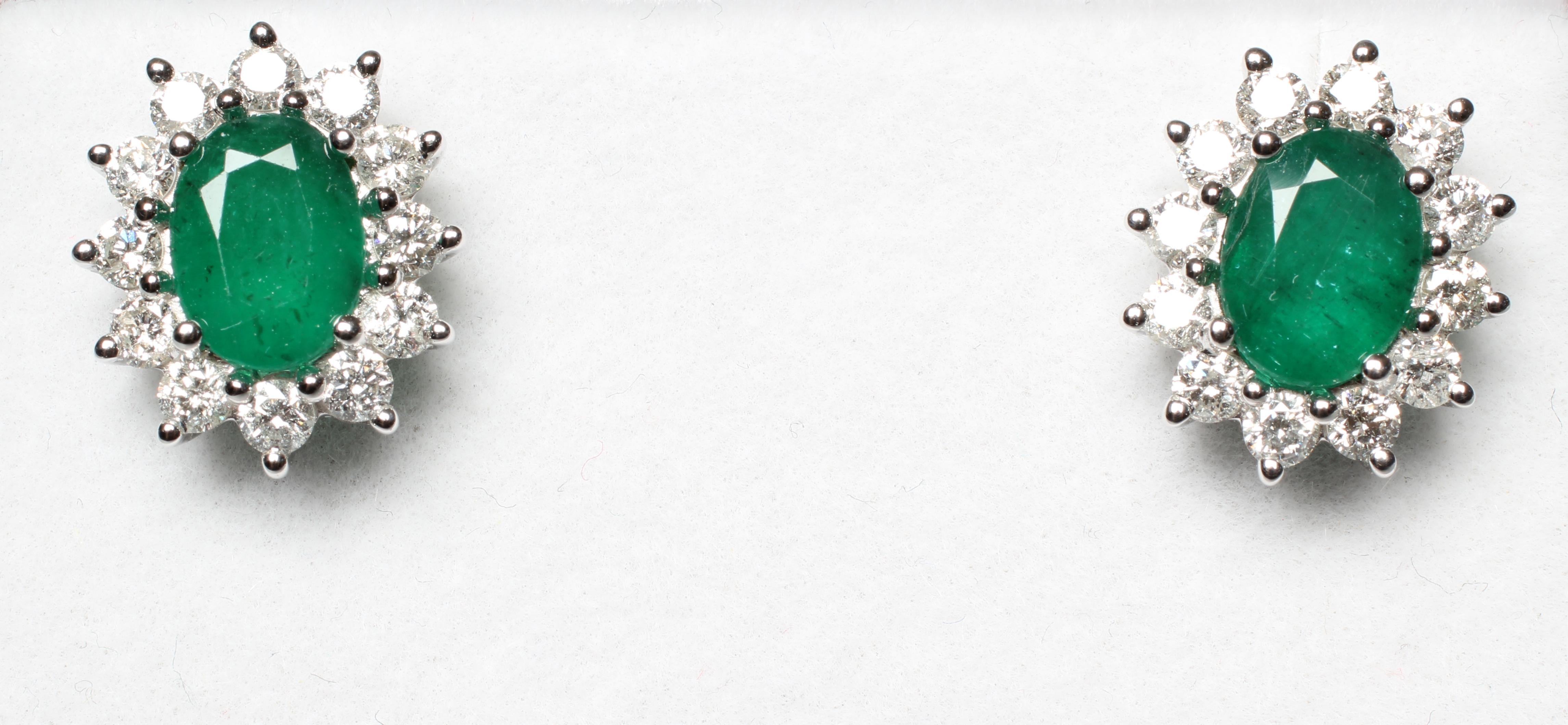 A PAIR OF EMERALD AND DIAMOND CLUSTER EAR STUDS, the oval facet cut emeralds claw set to borders, Image