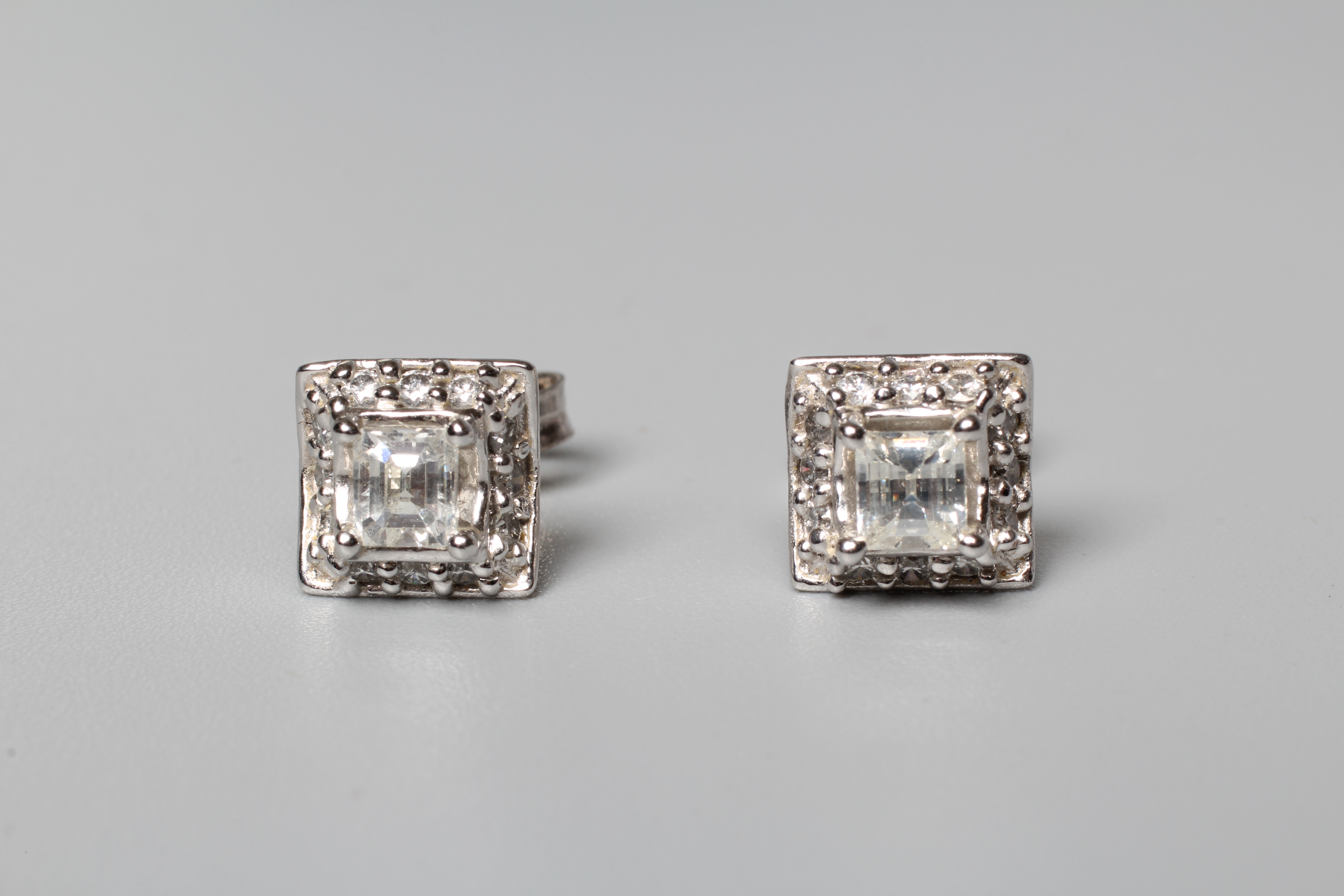 A PAIR OF DIAMOND EAR STUDS, the central square cut stones claw set to a border small round Image