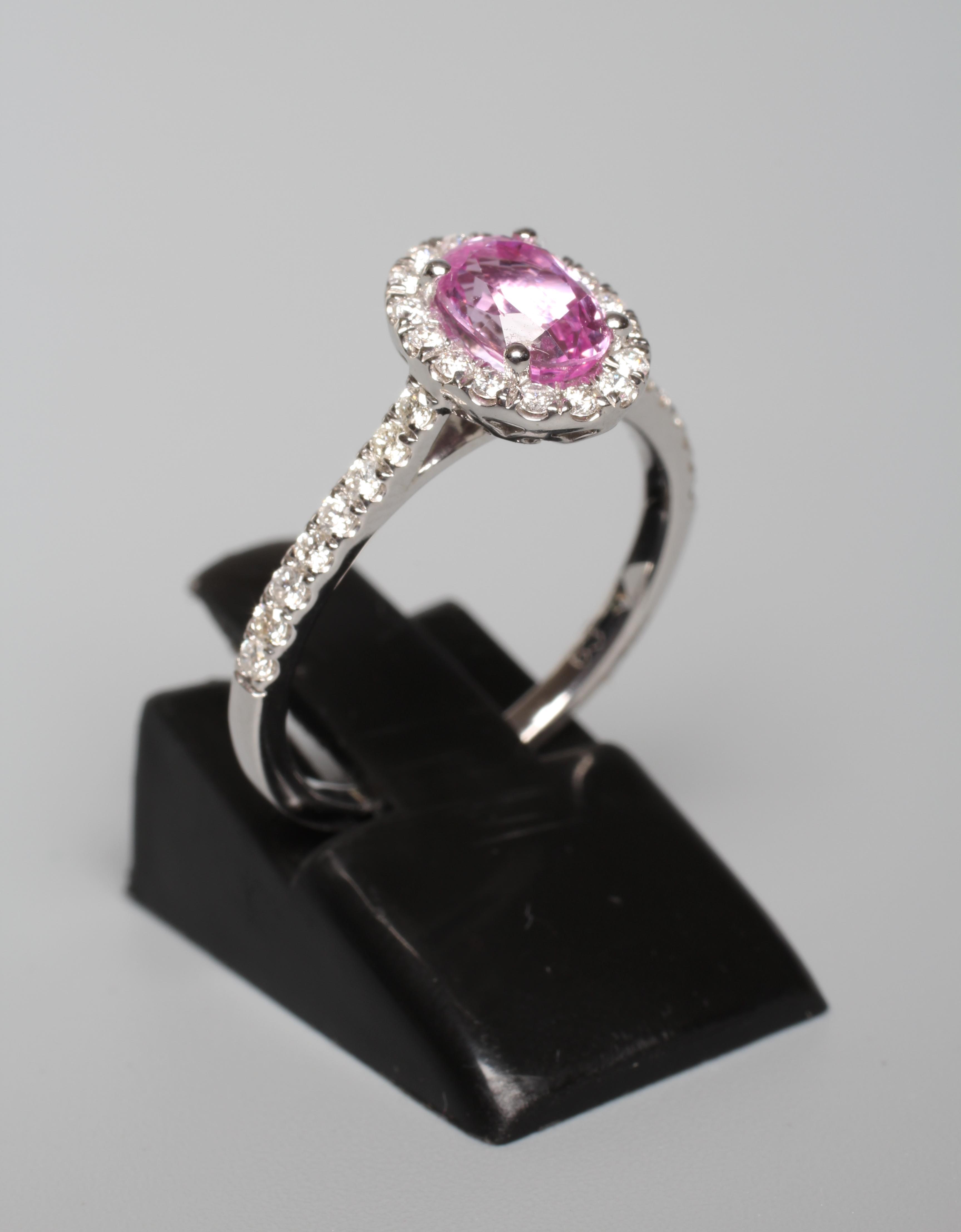 A PINK SAPPHIRE AND DIAMOND CLUSTER RING, the oval facet cut sapphire claw set to a border of small Image