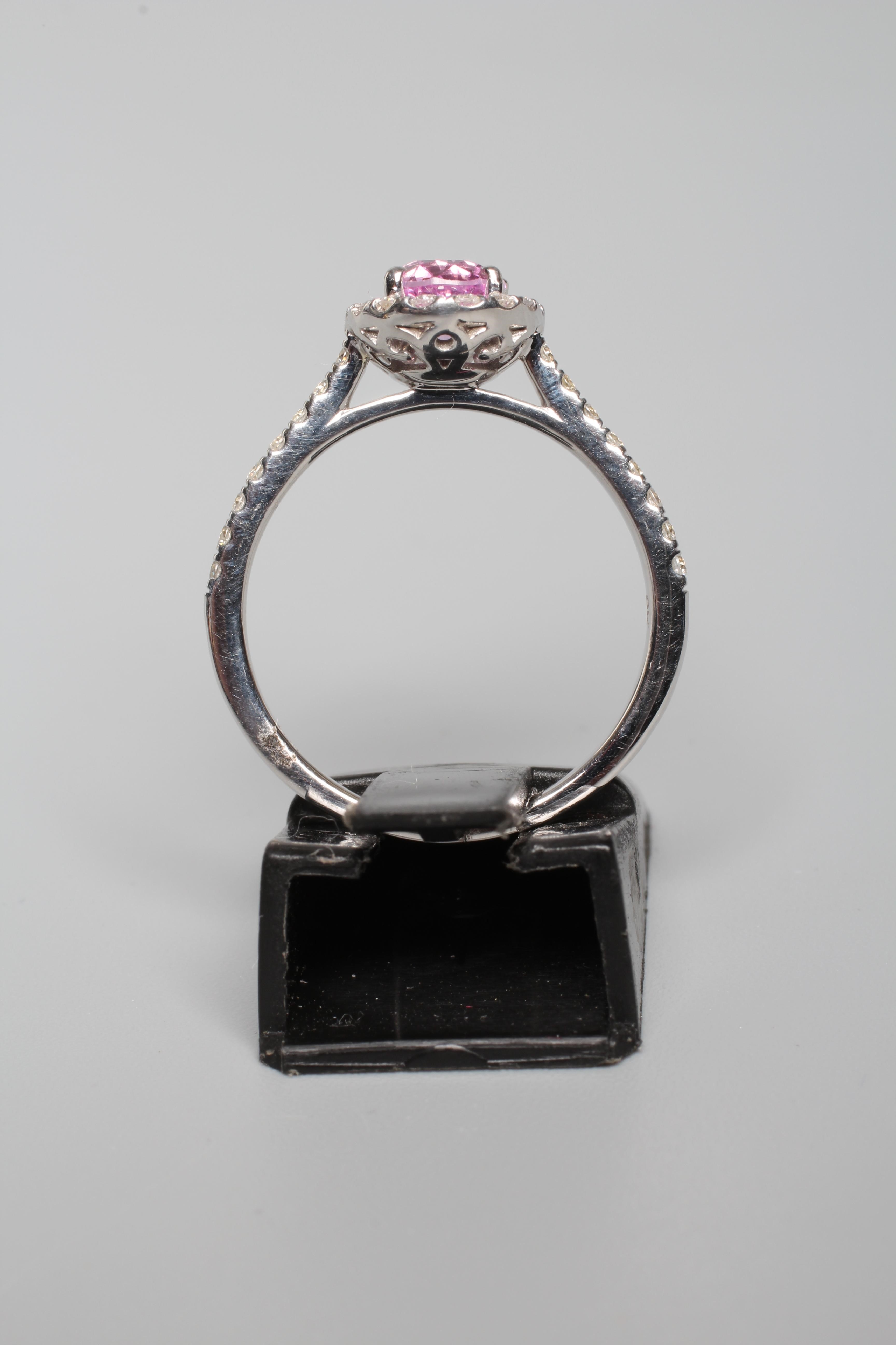 A PINK SAPPHIRE AND DIAMOND CLUSTER RING, the oval facet cut sapphire claw set to a border of small Image