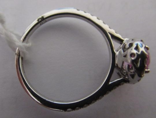 A PINK SAPPHIRE AND DIAMOND CLUSTER RING, the oval facet cut sapphire claw set to a border of small Image
