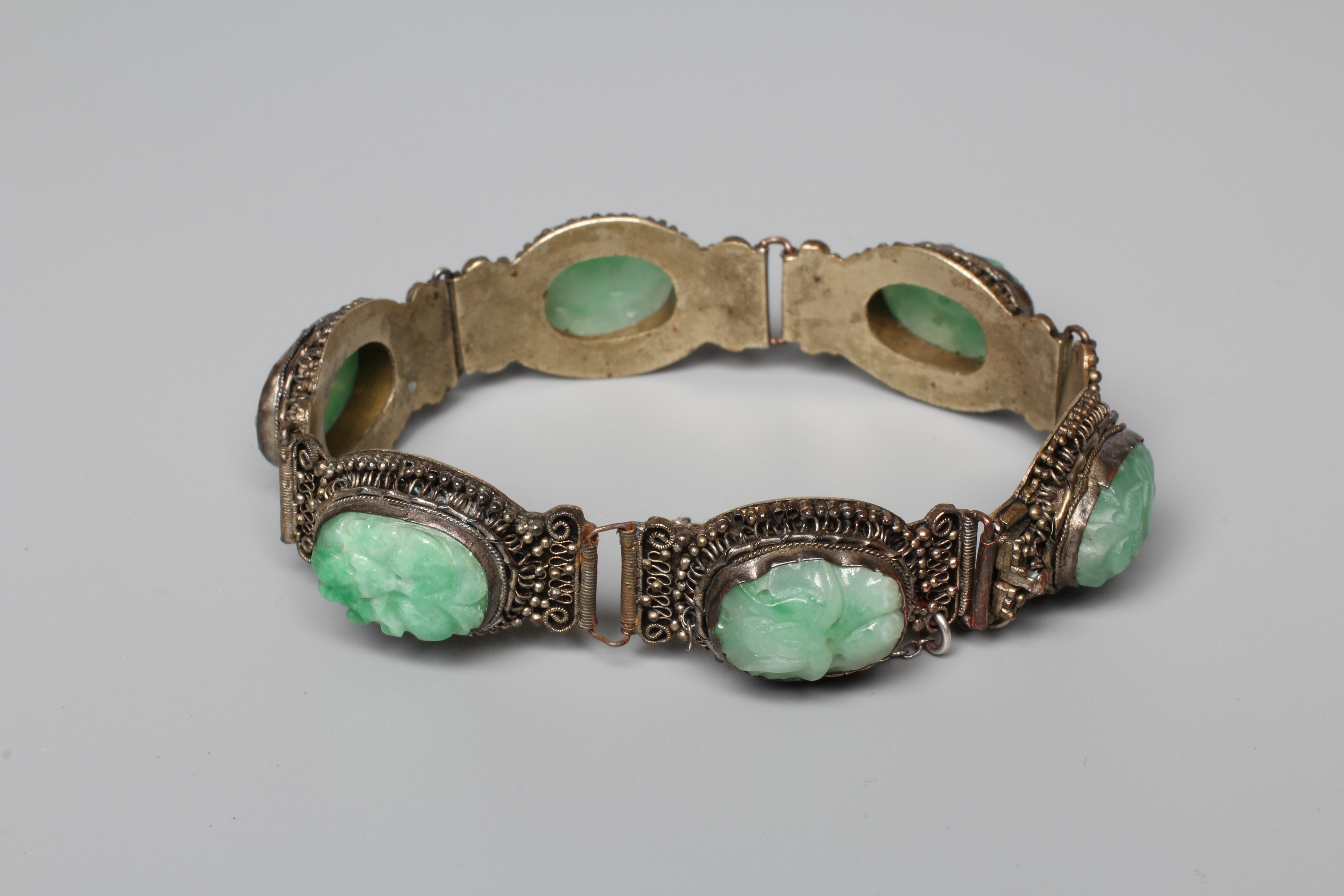 A CHINESE BRACELET, set with six oval flower carved jade panels to a filigree style frame, unmarked Image