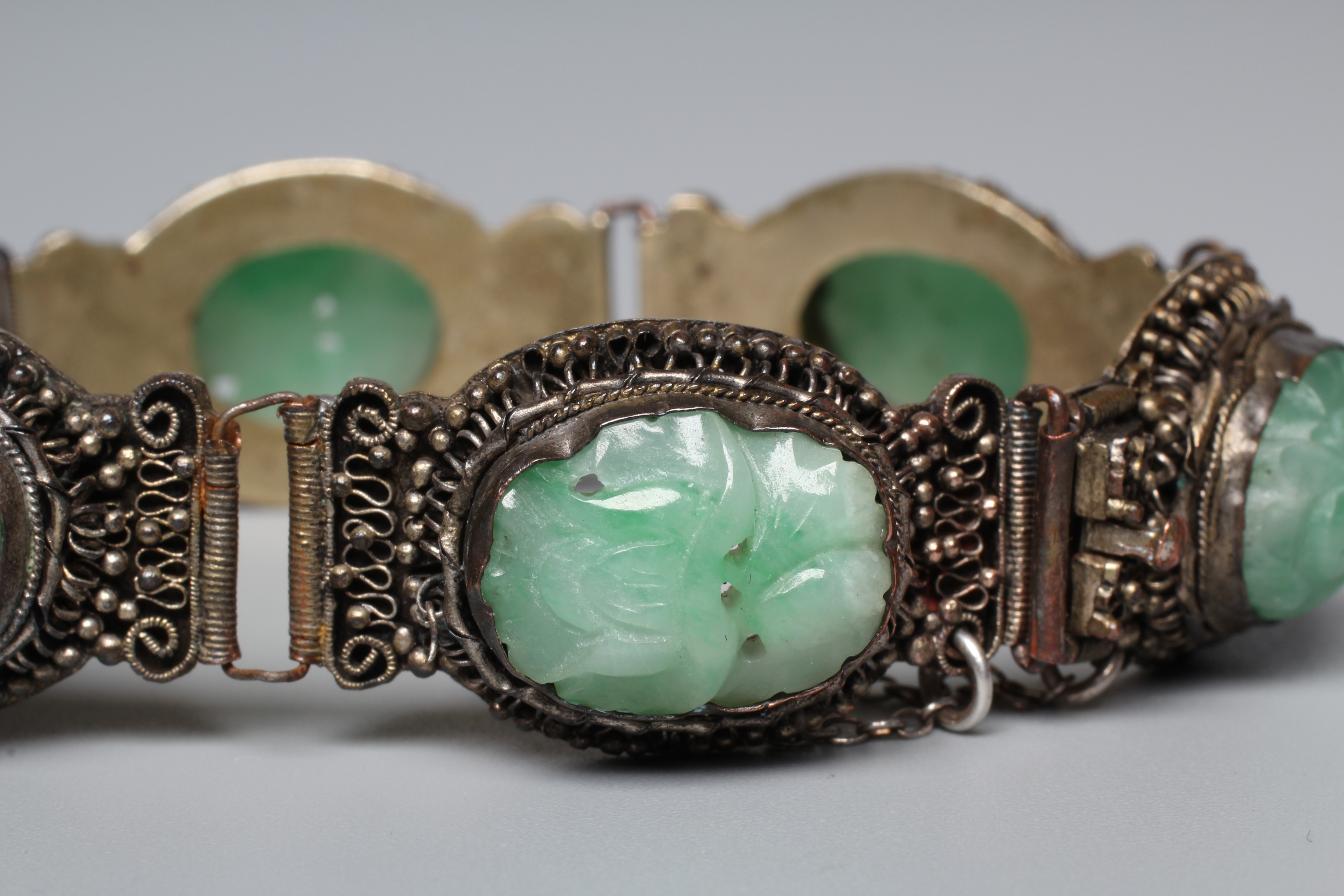 A CHINESE BRACELET, set with six oval flower carved jade panels to a filigree style frame, unmarked Image