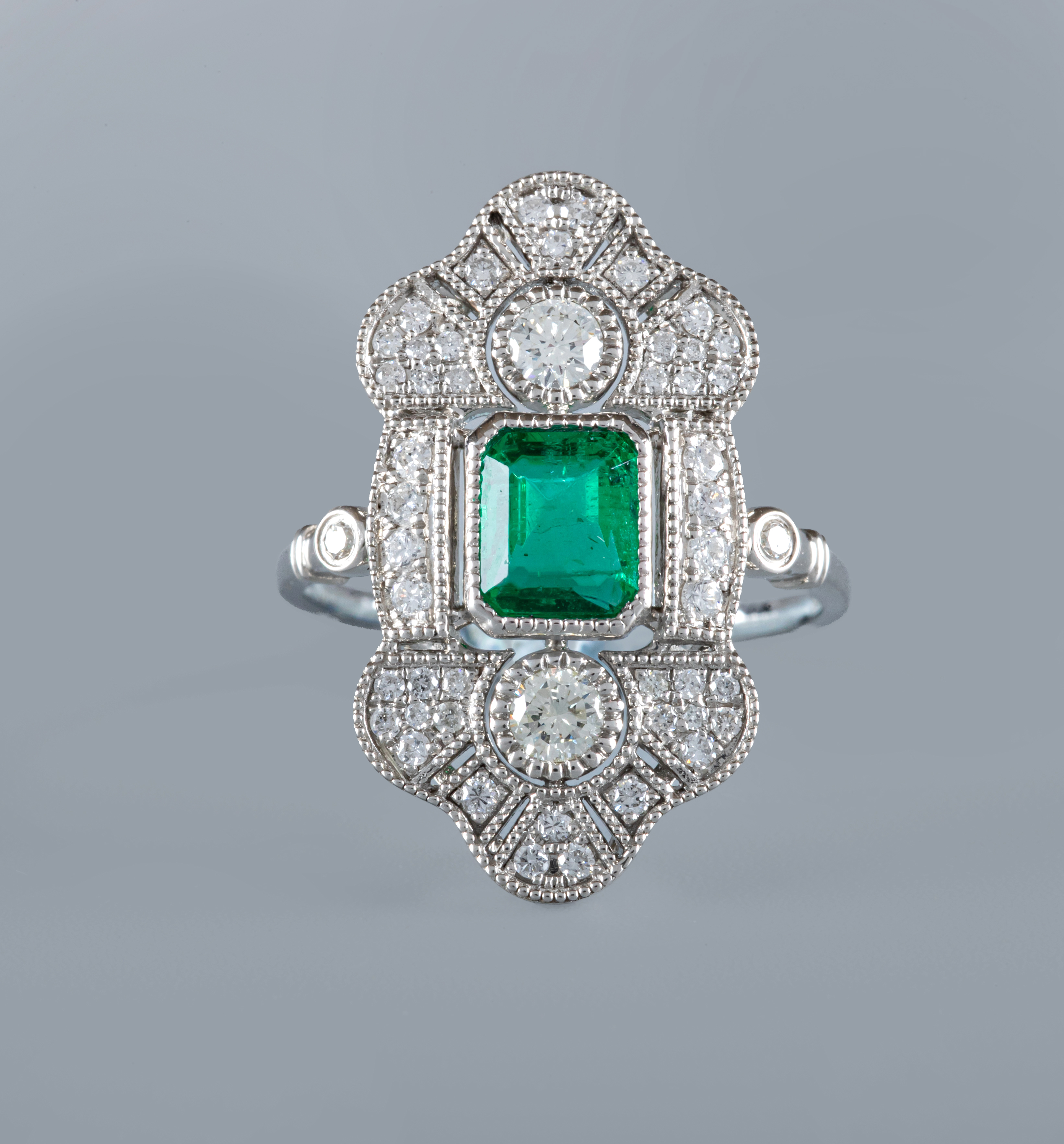 AN ART DECO STYLE EMERALD AND DIAMOND COCKTAIL RING, the central step cut emerald collet set to an Image