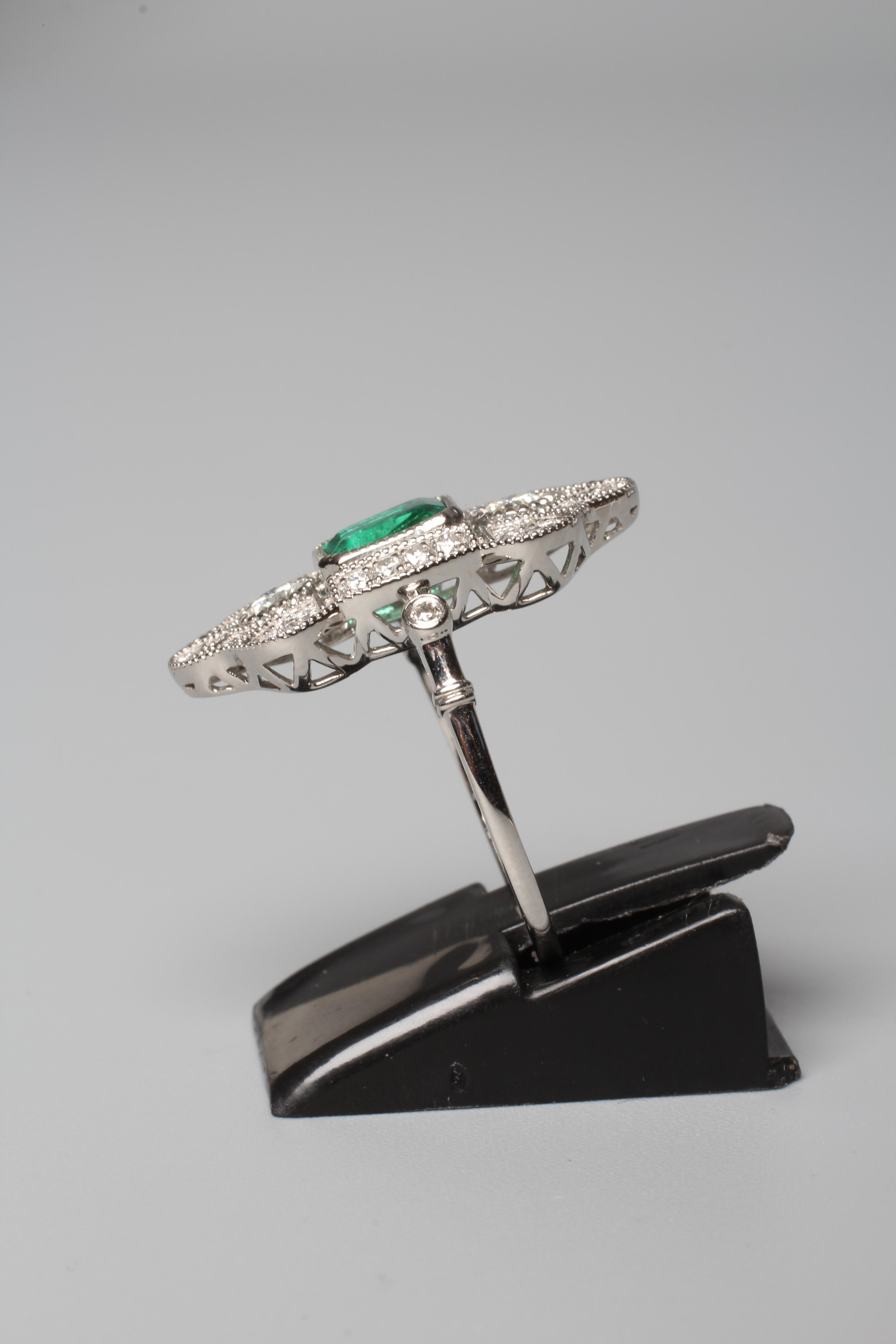 AN ART DECO STYLE EMERALD AND DIAMOND COCKTAIL RING, the central step cut emerald collet set to an Image
