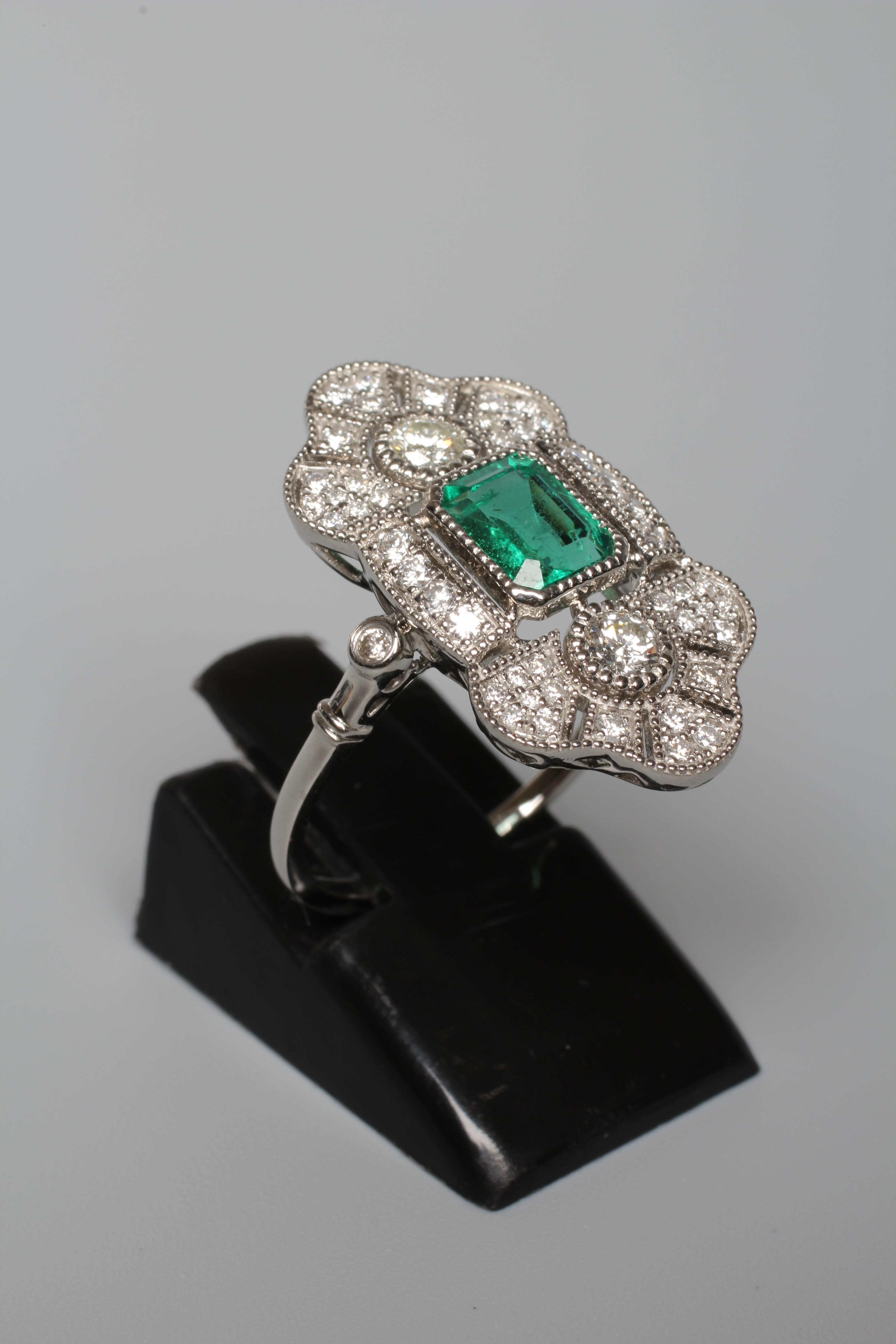 AN ART DECO STYLE EMERALD AND DIAMOND COCKTAIL RING, the central step cut emerald collet set to an Image
