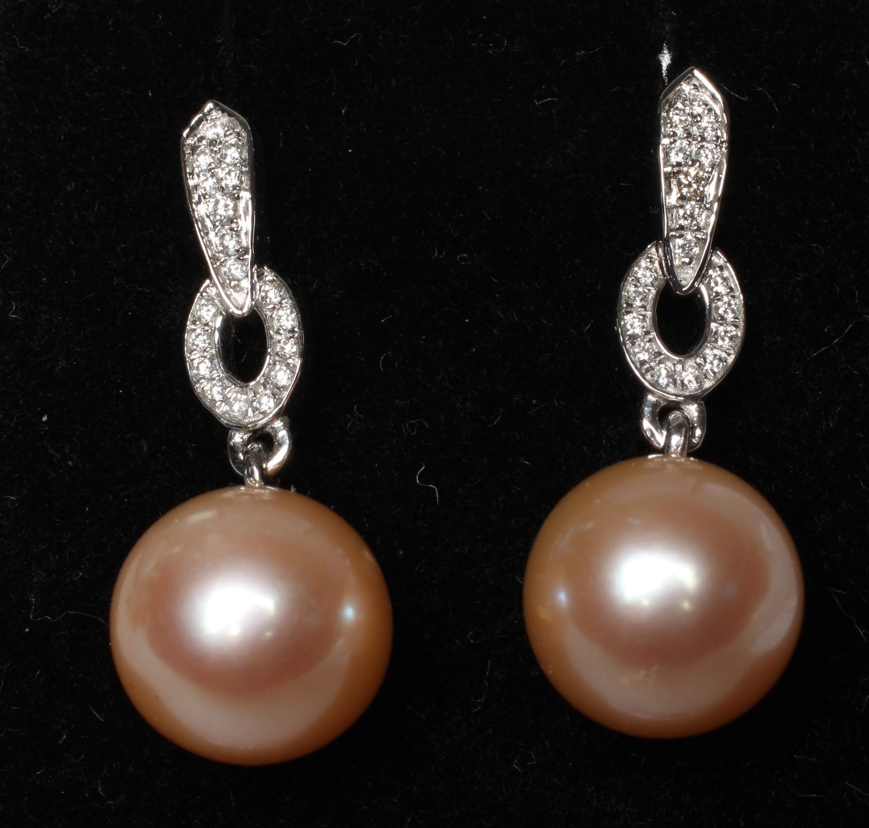 A PAIR OF CULTURED PEARL EAR DROPS, the peach coloured pearls peg set and pendant from an Art Deco Image