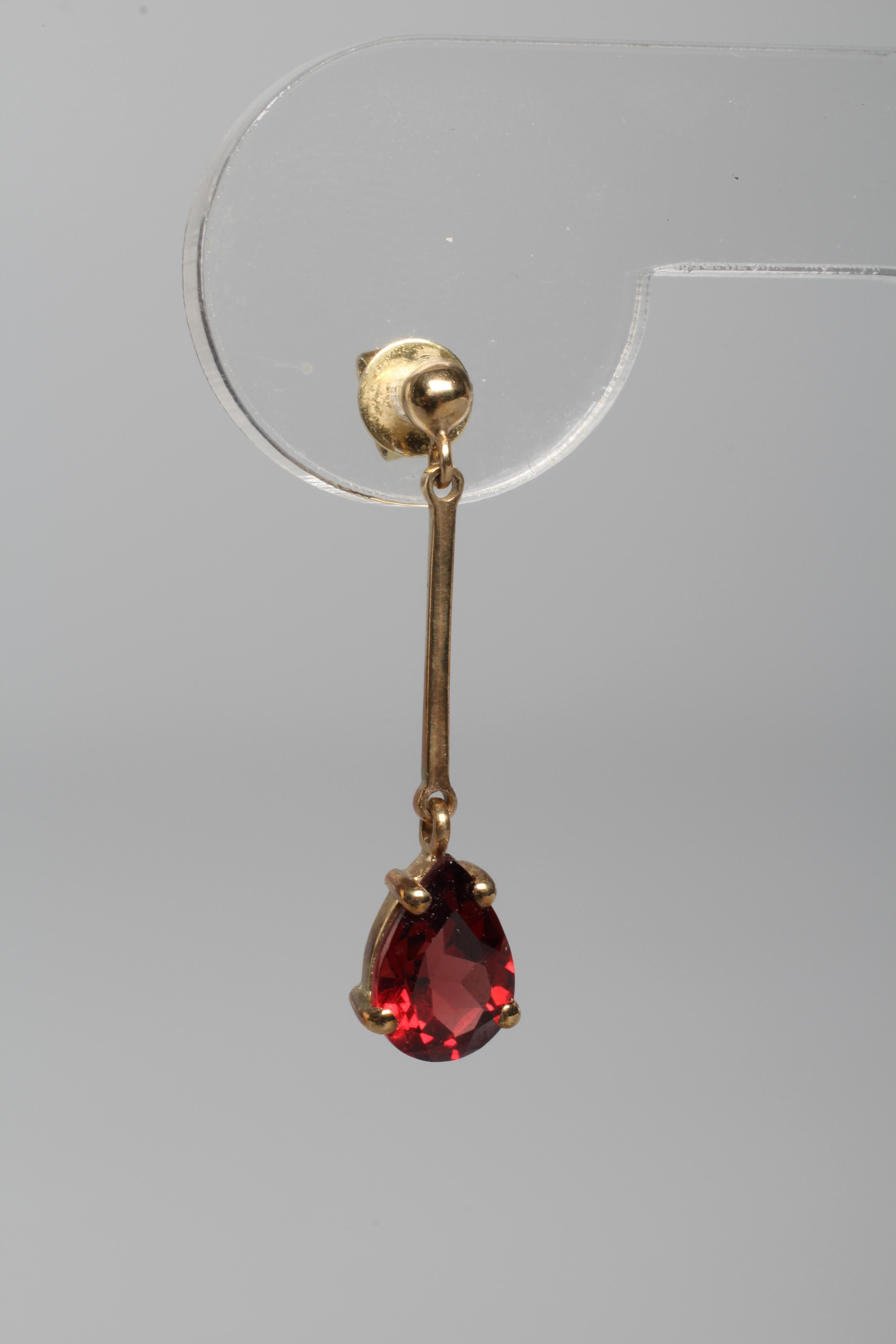 A PAIR OF GARNET DROP EAR STUDS, the pear cut stones pendant from knife edge bars and a plain stud Image