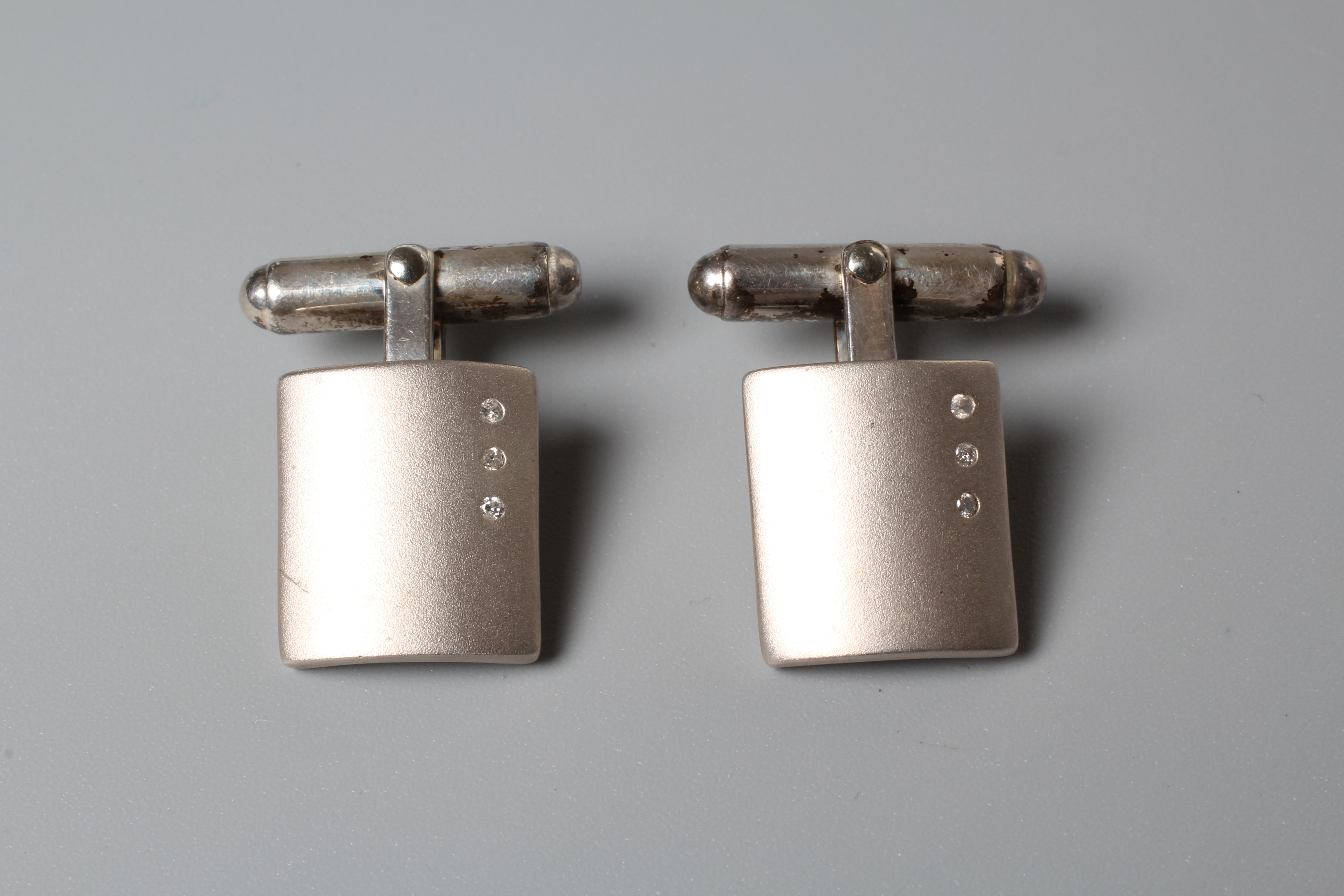 A PAIR OF SILVER CUFFLINKS, each matt polished oblong link set with three small diamonds, stamped Image